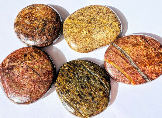 Several bronzite palm stones on white bench