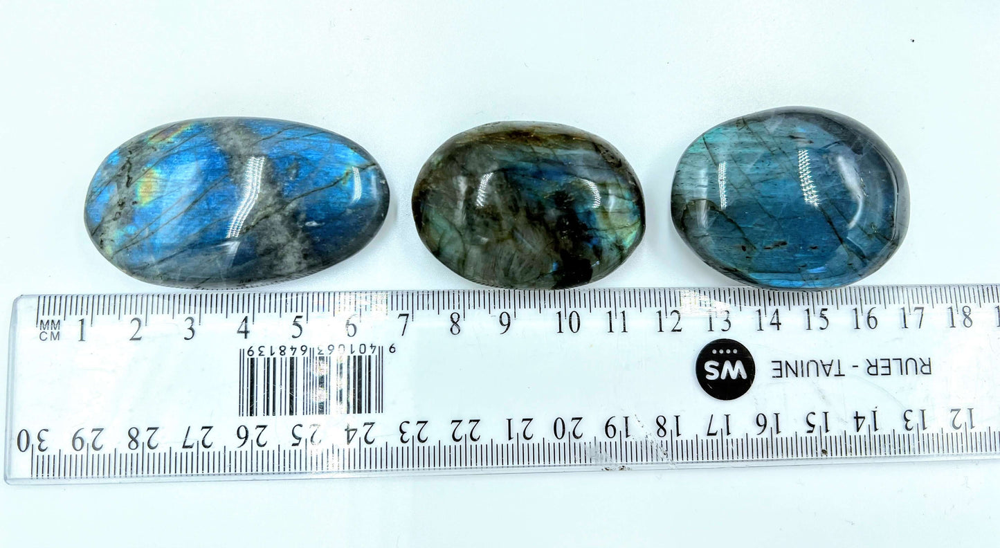 Polished labradorite stone displaying iridescent colors and intricate patterns with ruler to show size