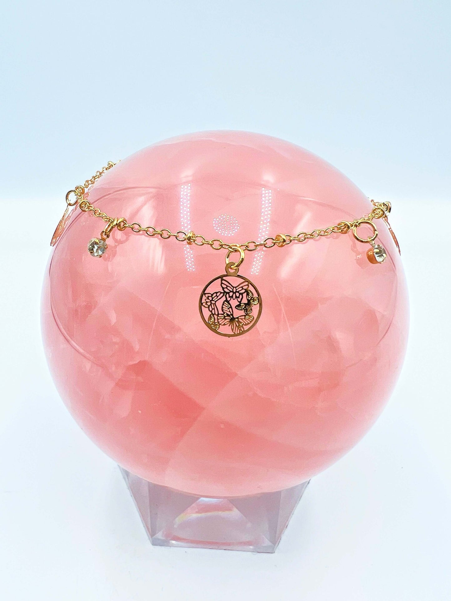 Ankle bracelets sitting on a large rose quartz sphere.