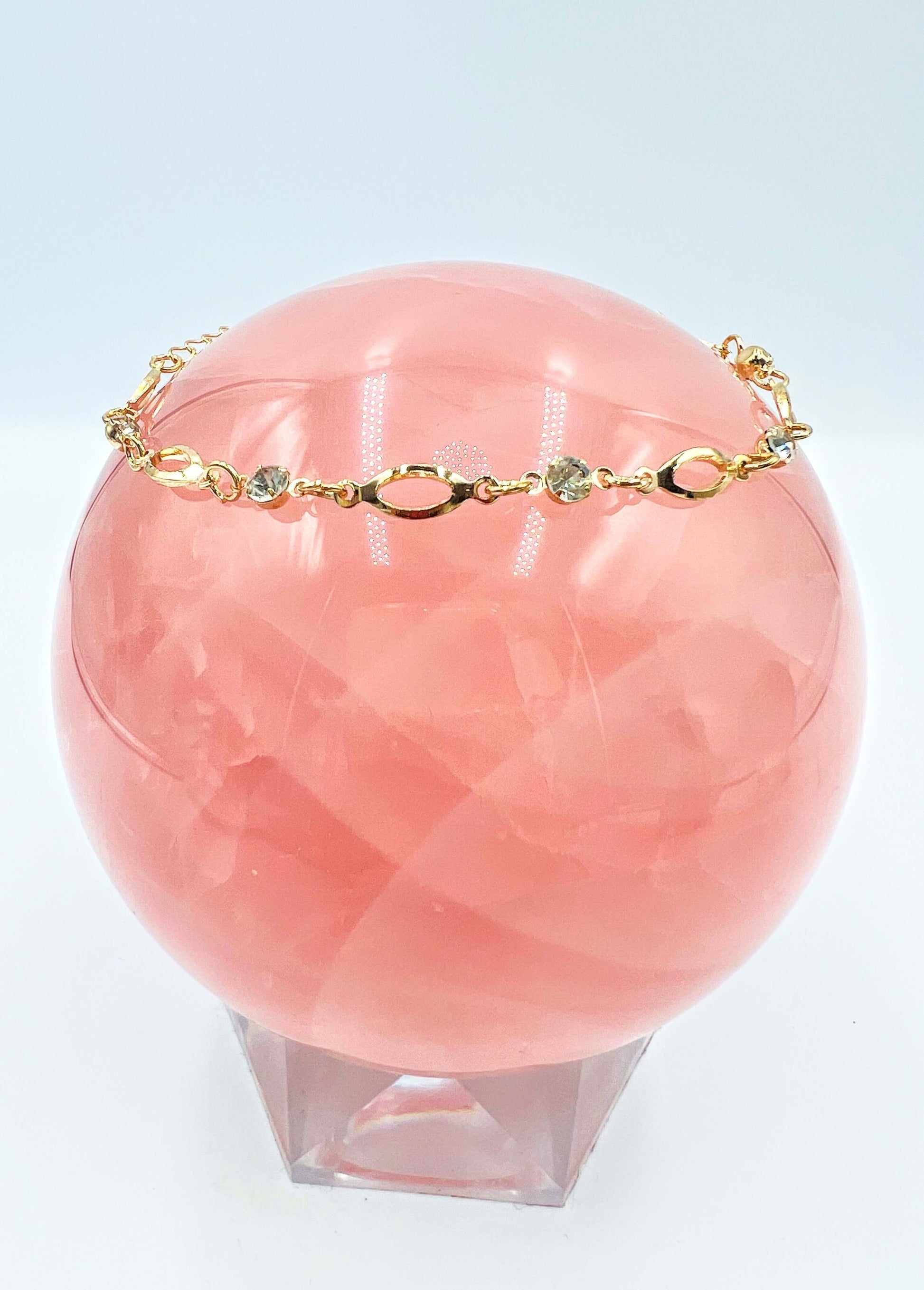 Ankle bracelets sitting on a large rose quartz sphere.