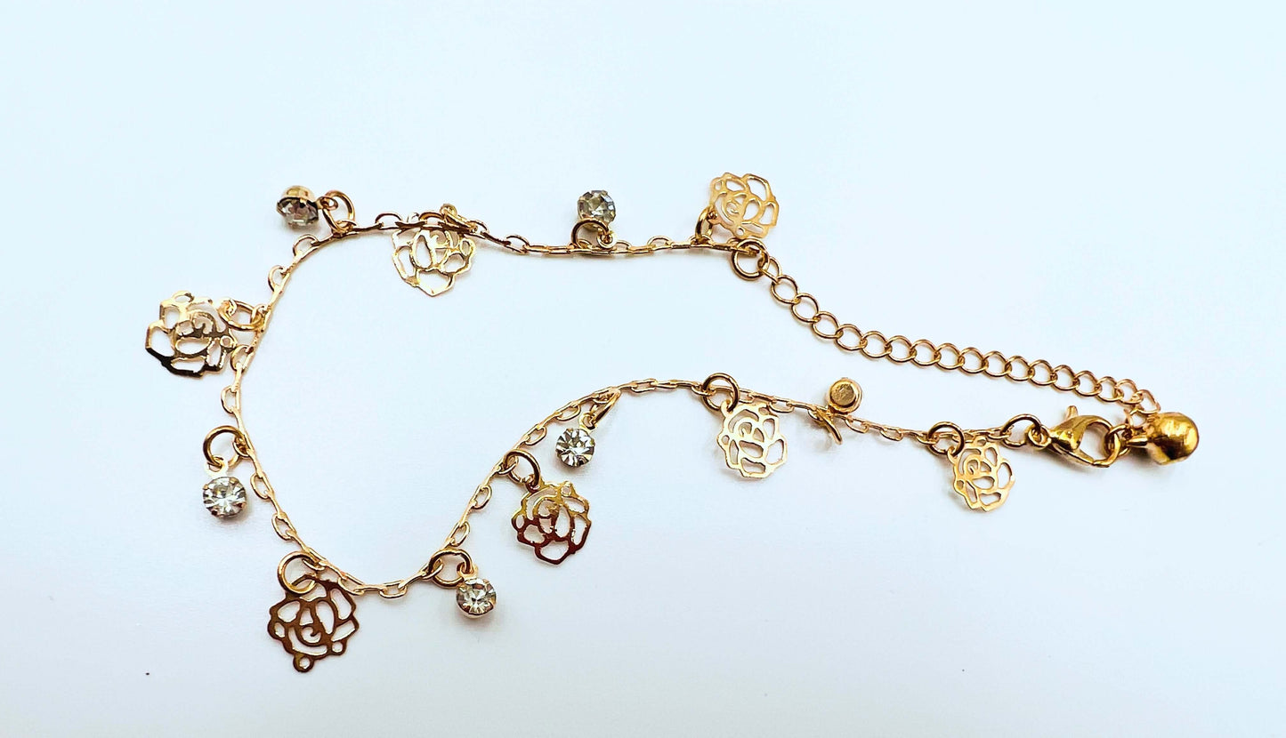 Ankle bracelet gold colour sitting on white surface. 