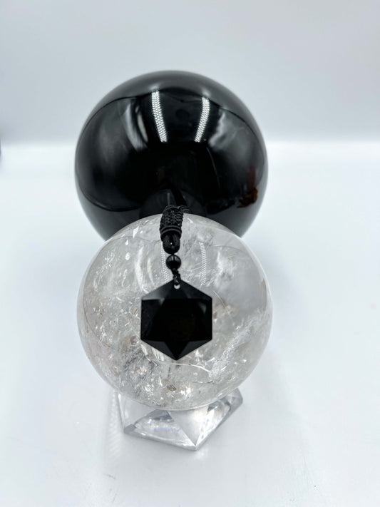 Black obsidian pendant resting on clear quartz sphere