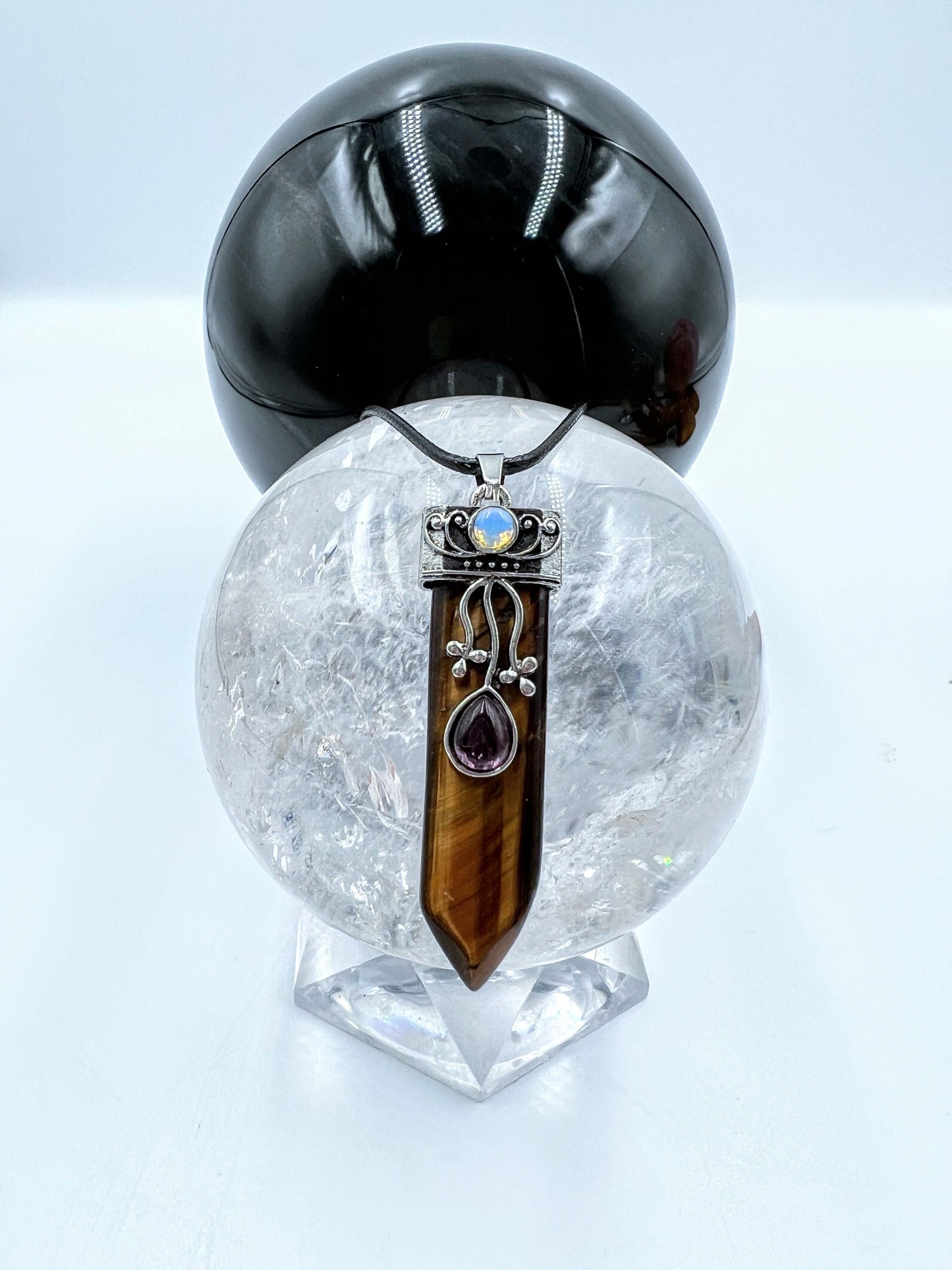 Tigers eye Crystal pendant sitting on clear quartz sphere.