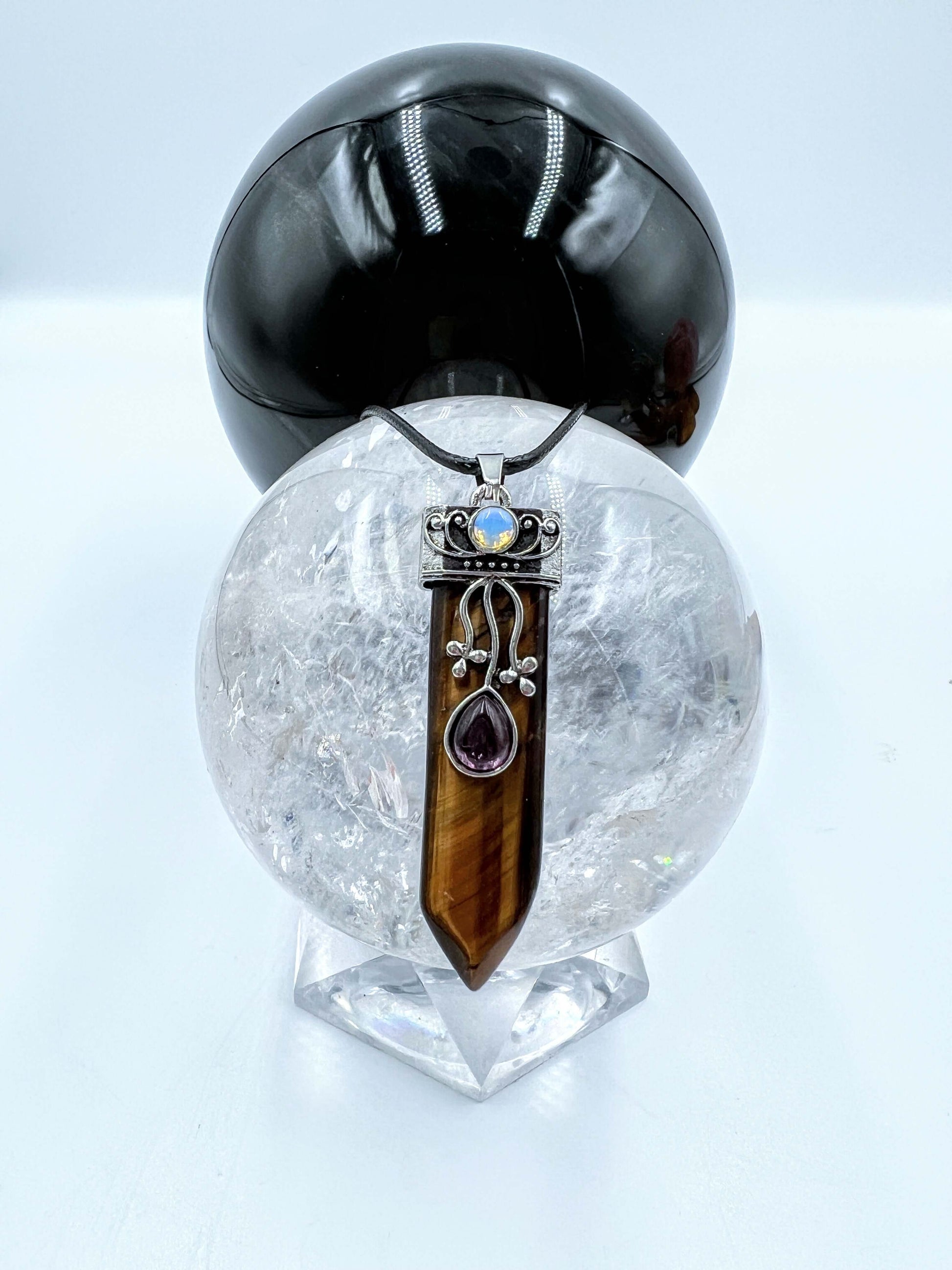 Tigers eye Crystal pendant sitting on clear quartz sphere.