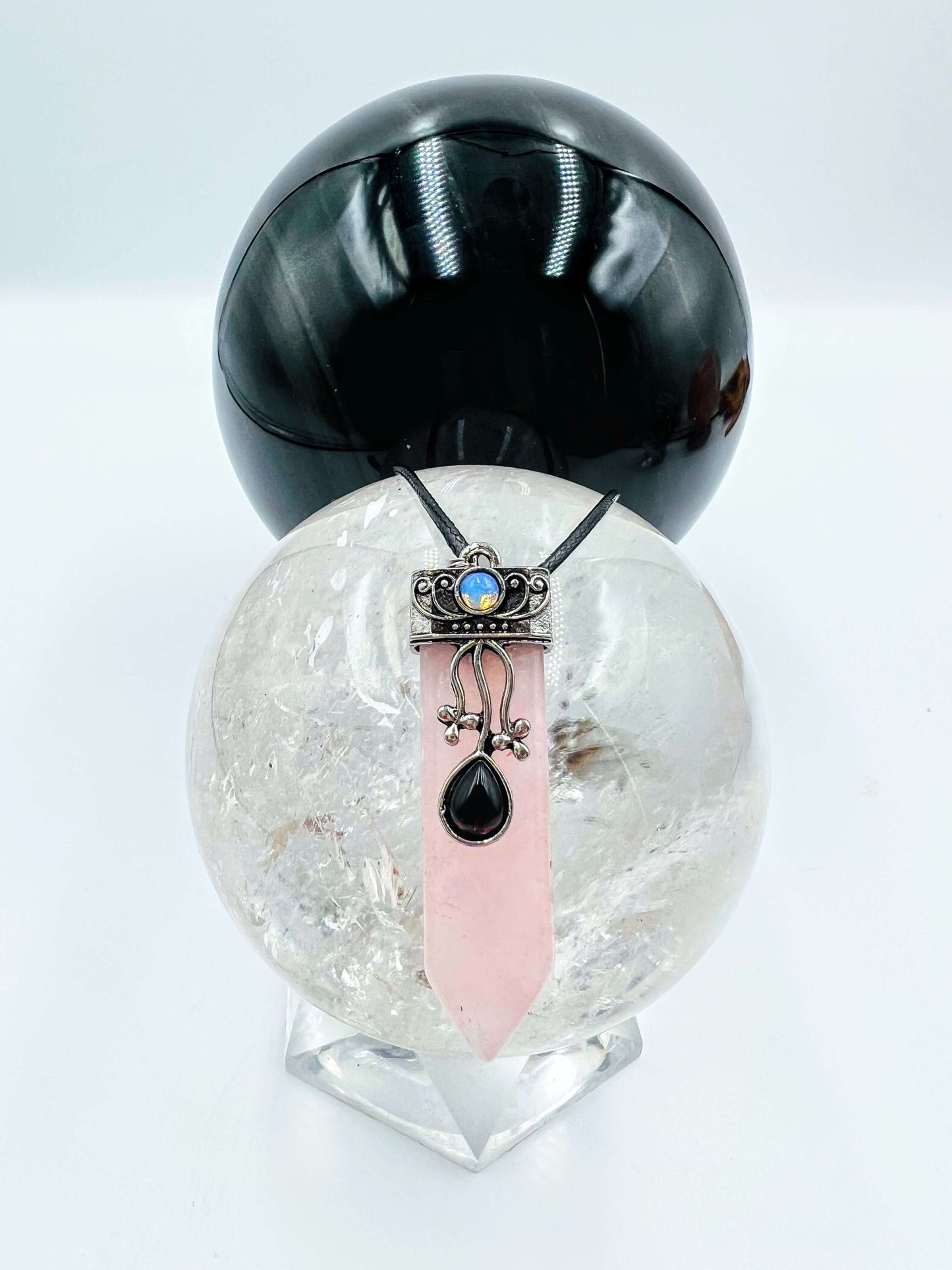 Rose quartz Crystal pendant sitting on clear quartz sphere.