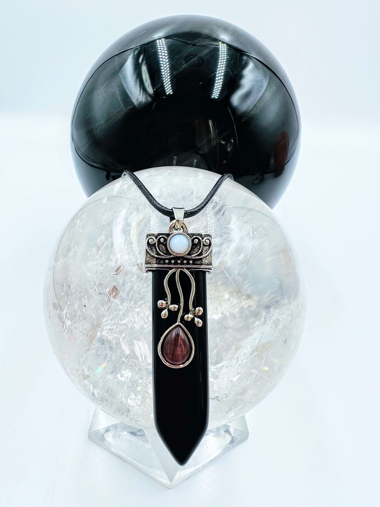 Black obsidian Crystal pendant sitting on clear quartz sphere.