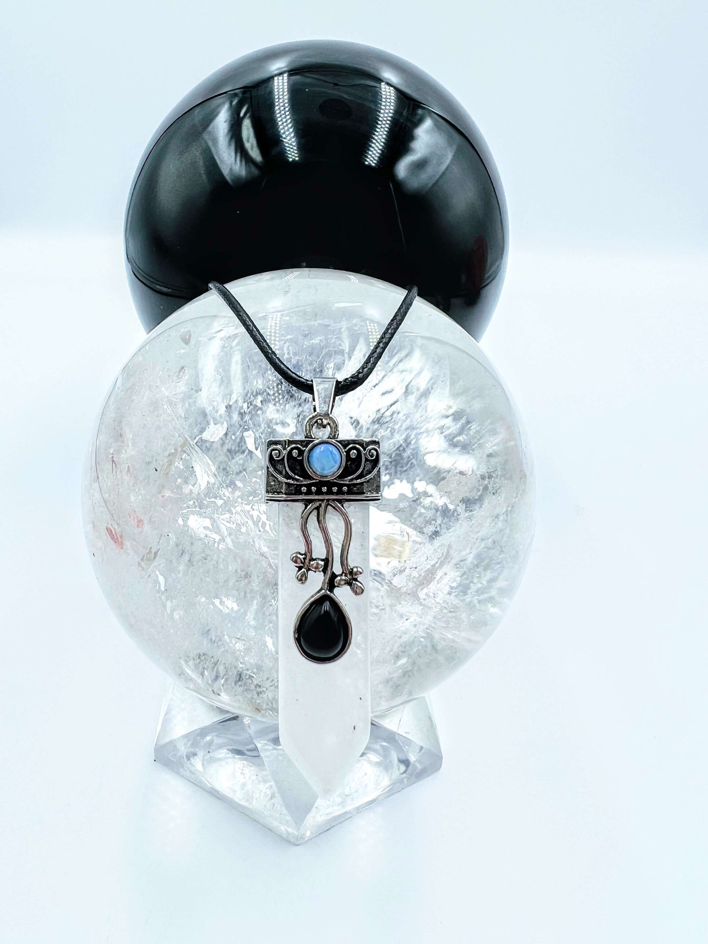 Clear quartz Crystal pendant sitting on clear quartz sphere.