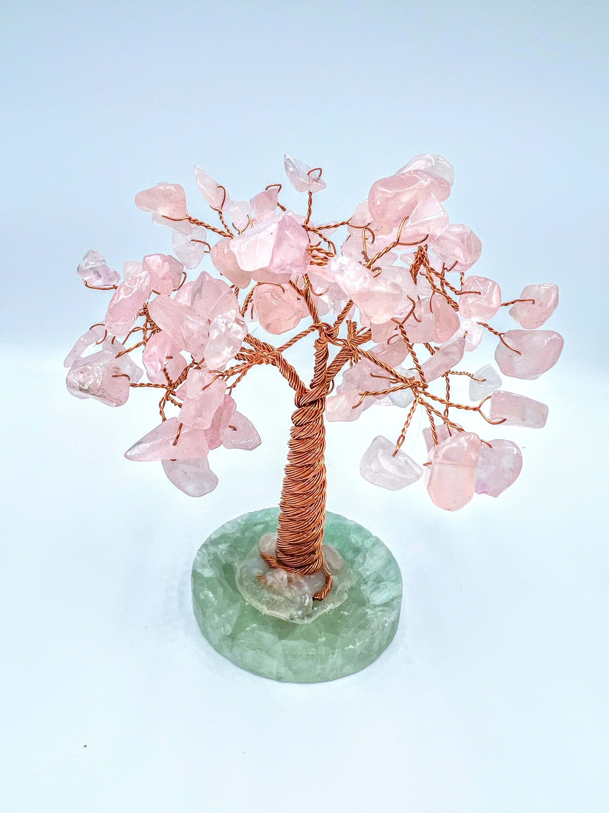 Rose quartz crystal gem tree on white surface