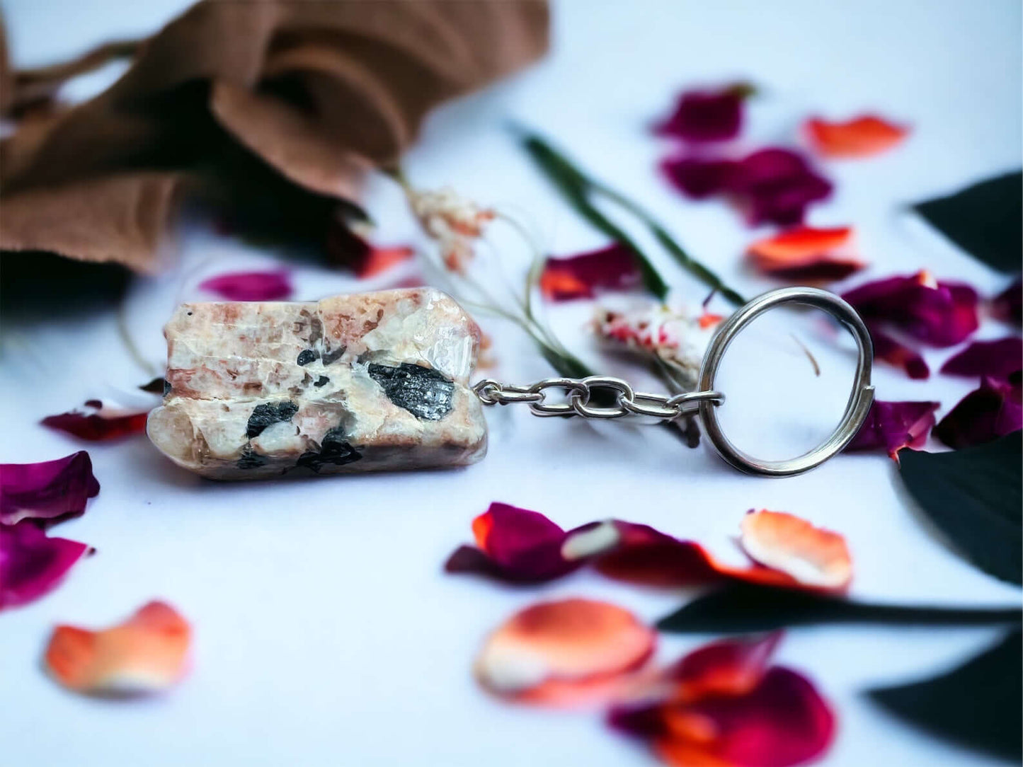 Crystal key rings on white surface with petals 