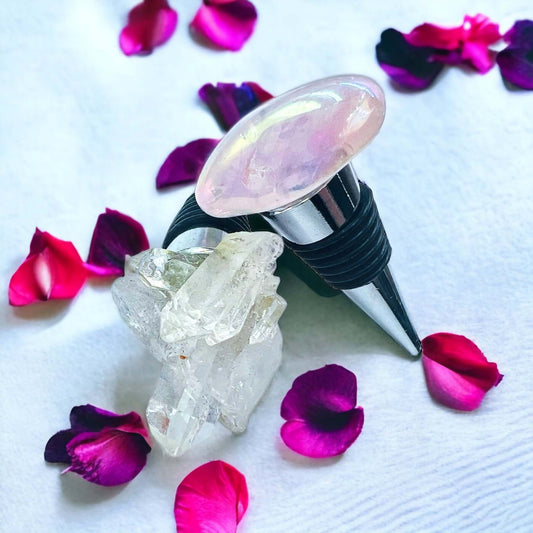 Rose quartz wine bottle stoppers on white surface with petals