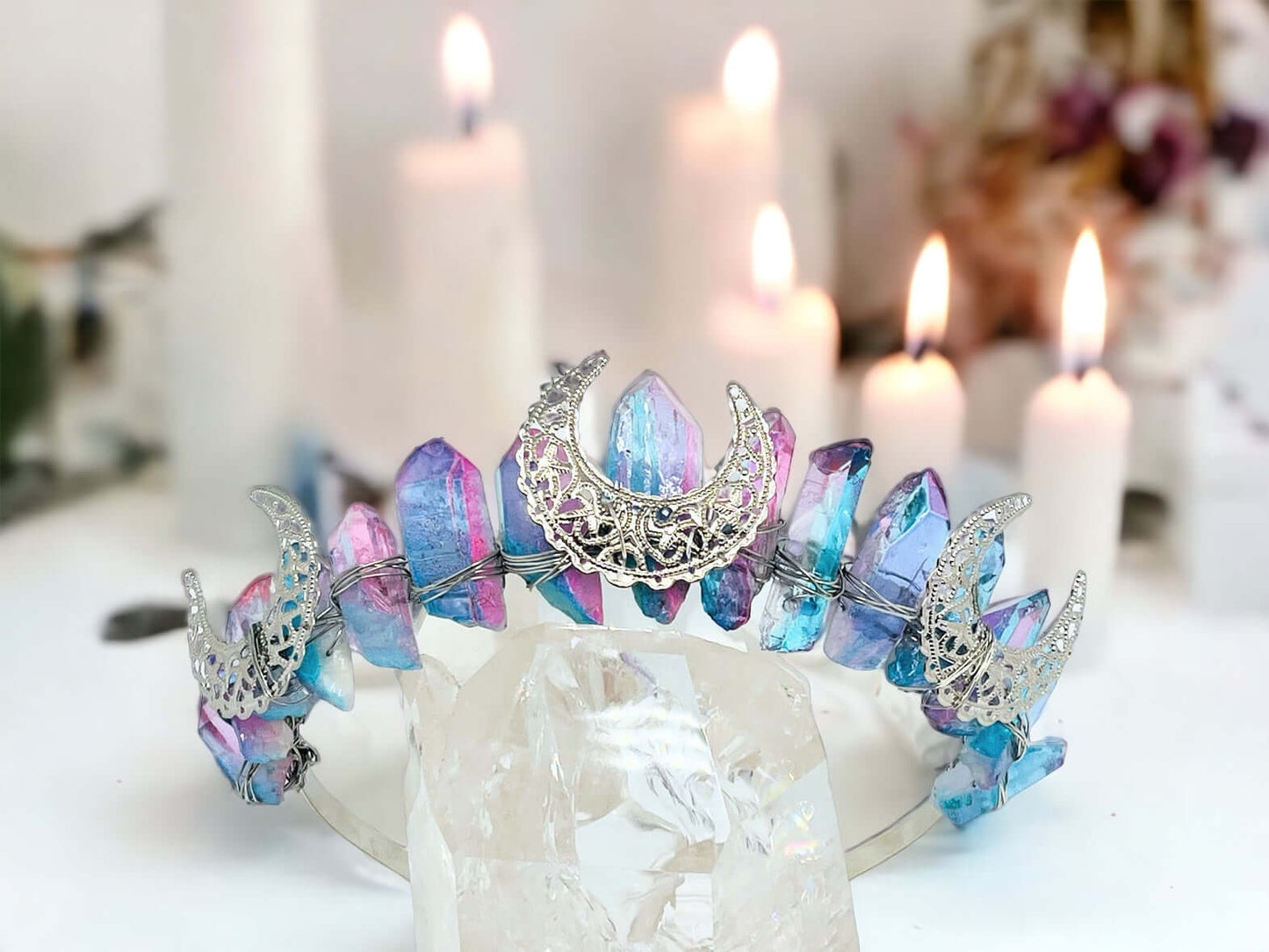 Crystal crown tiara on white surface with candles in background.