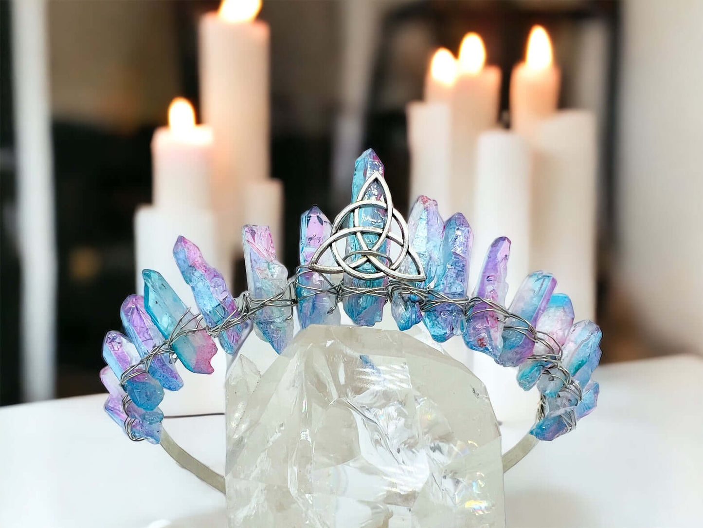 Crystal crown tiara on white surface with candles in background.