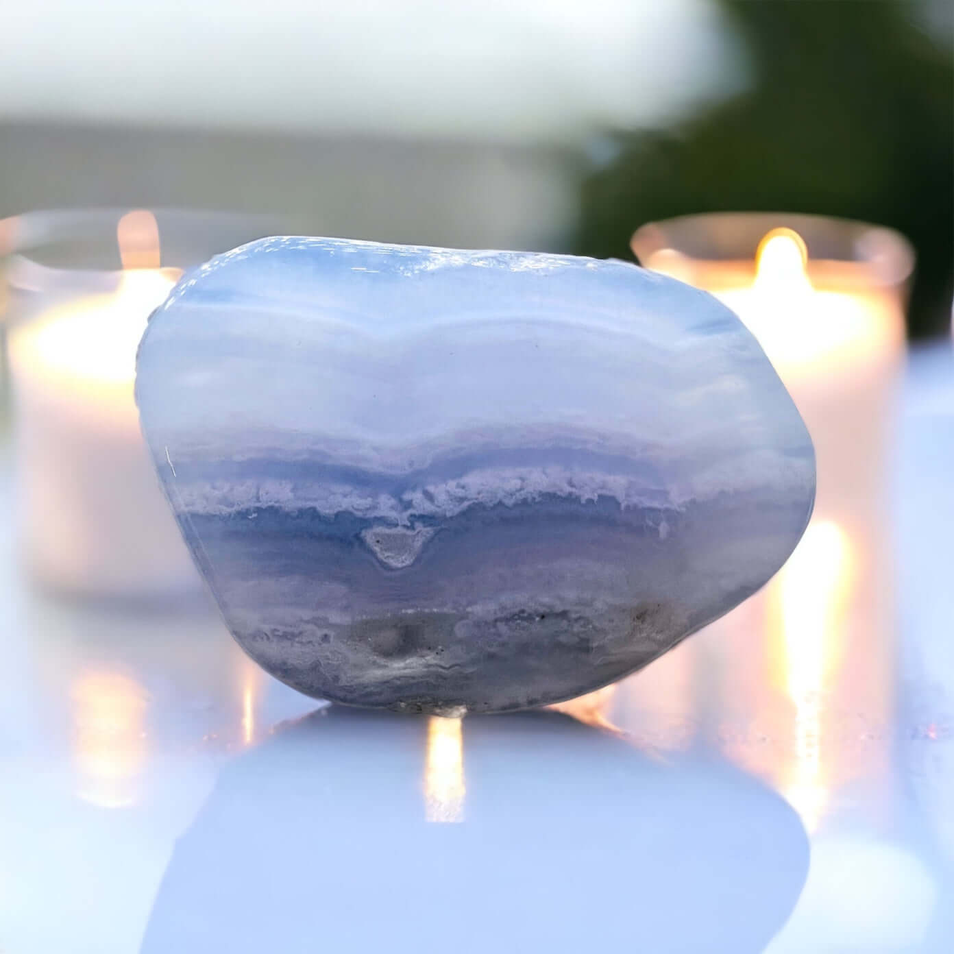 Blue lace agate stone on white surface with candle.