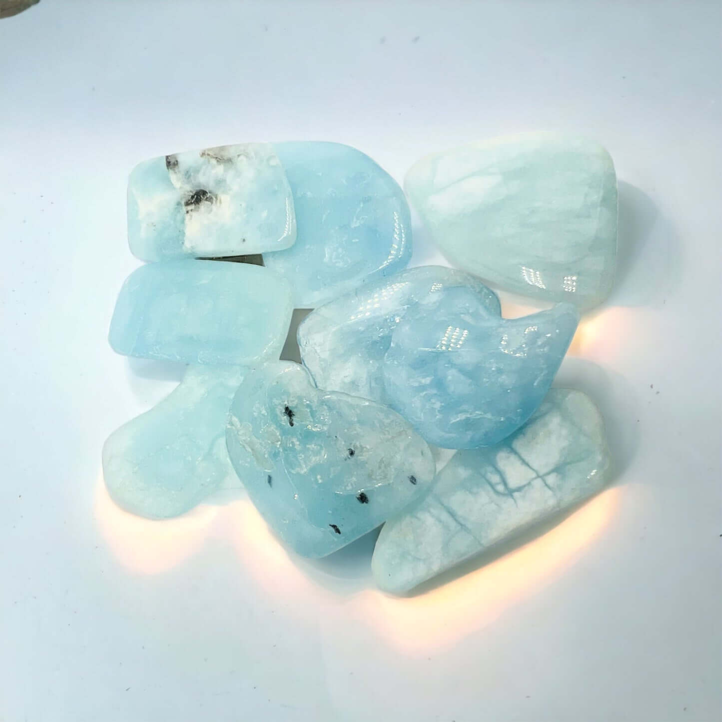 Aquamarine tumbled stones on white surface. 