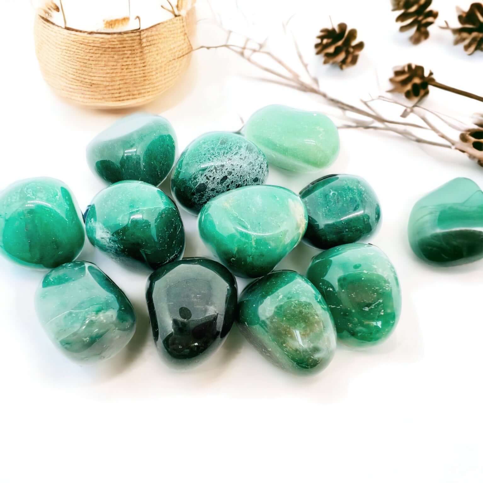 Green aventurine polished stones on a white background with candles.