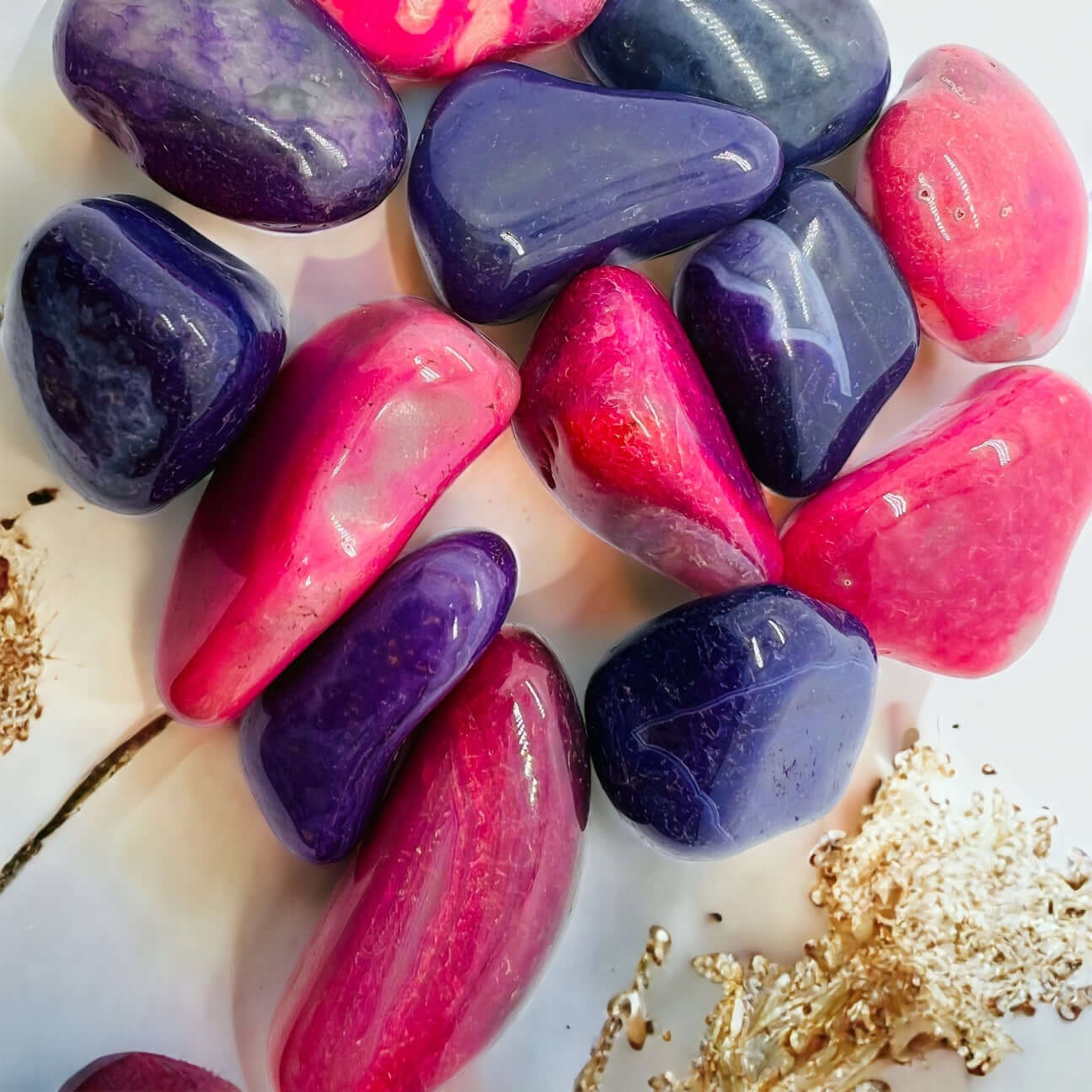 Bright Pink and purple tumbled agate stones on white surface. 