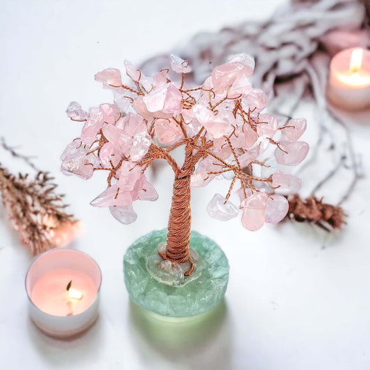 Rose quartz crystal tree on white surface. 