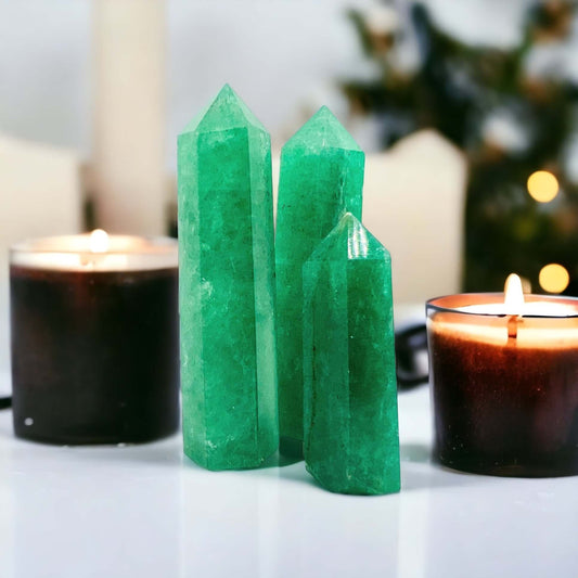 Green strawberry quartz points on white bench with candles. 