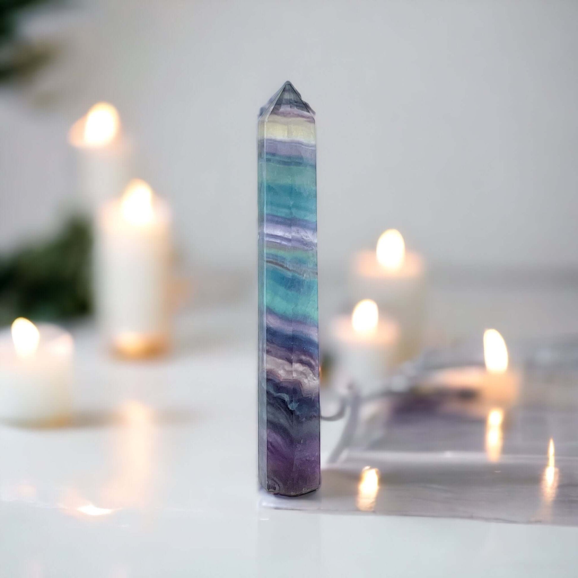 Fluorite point on white surface with candles in background 