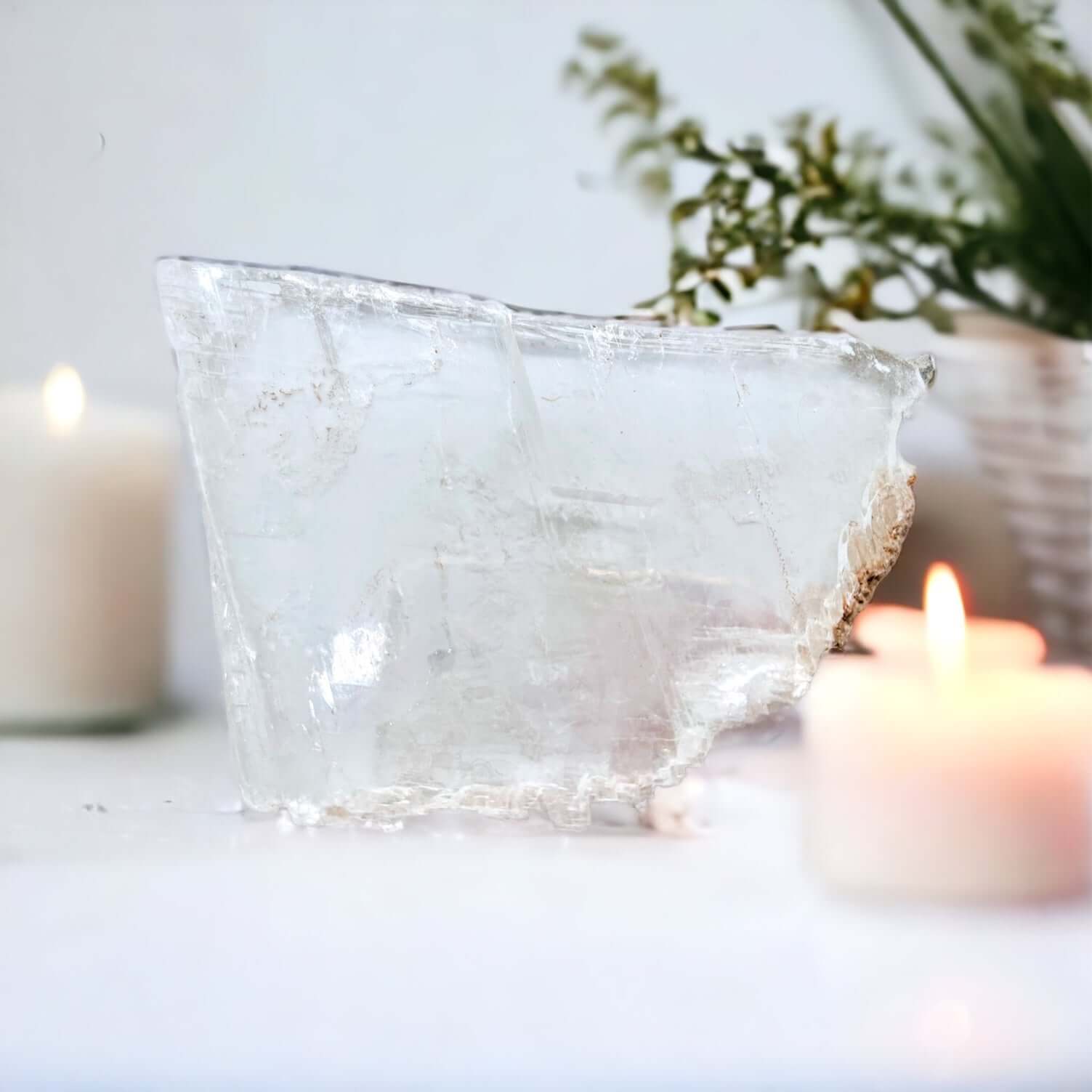 Clear selenite on white surface with candles