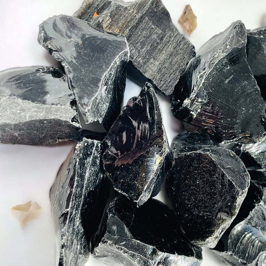 Several pieces of rough black obsidian on white surface