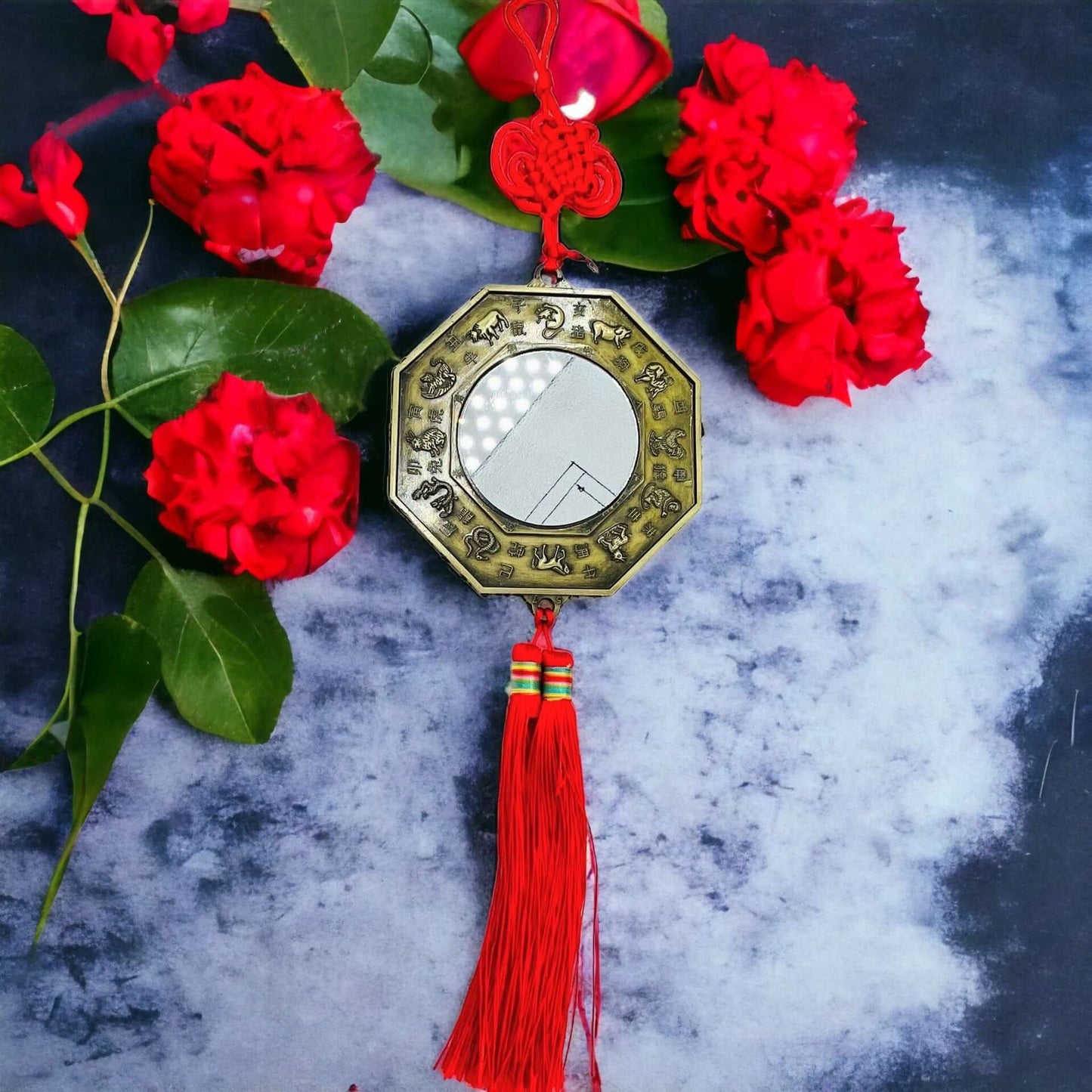 Feng Shui Bagua Mirror on Grey surface with red petals