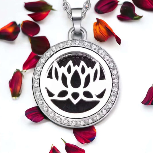 Diffuser locket necklace on white surface with scattered petals.