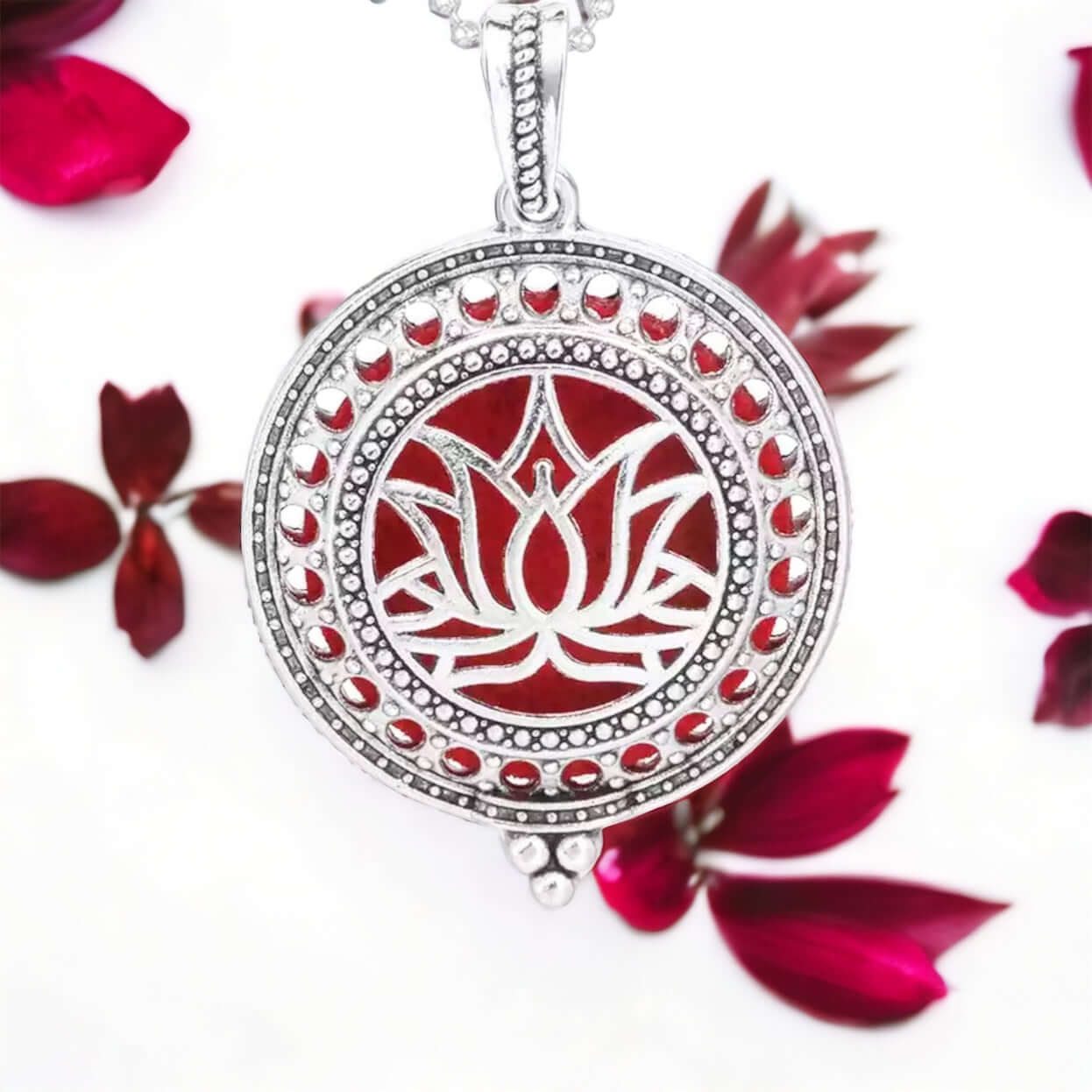 Lotus Diffuser locket on white surface with scattered petals.