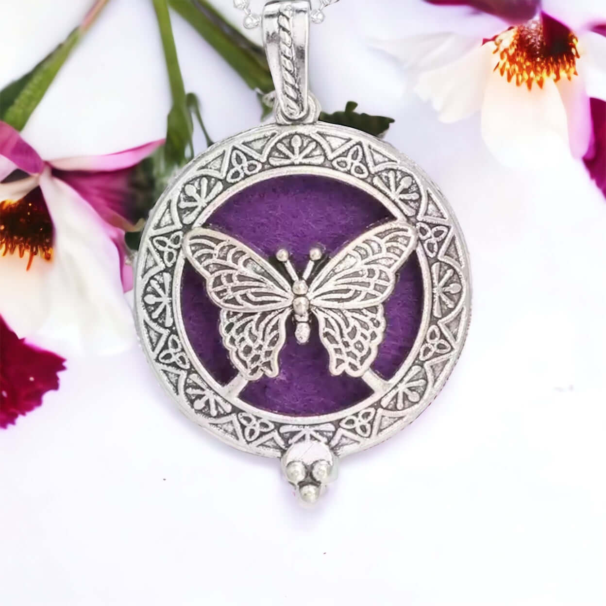 Butterfly Diffuser locket on white surface with scattered petals.