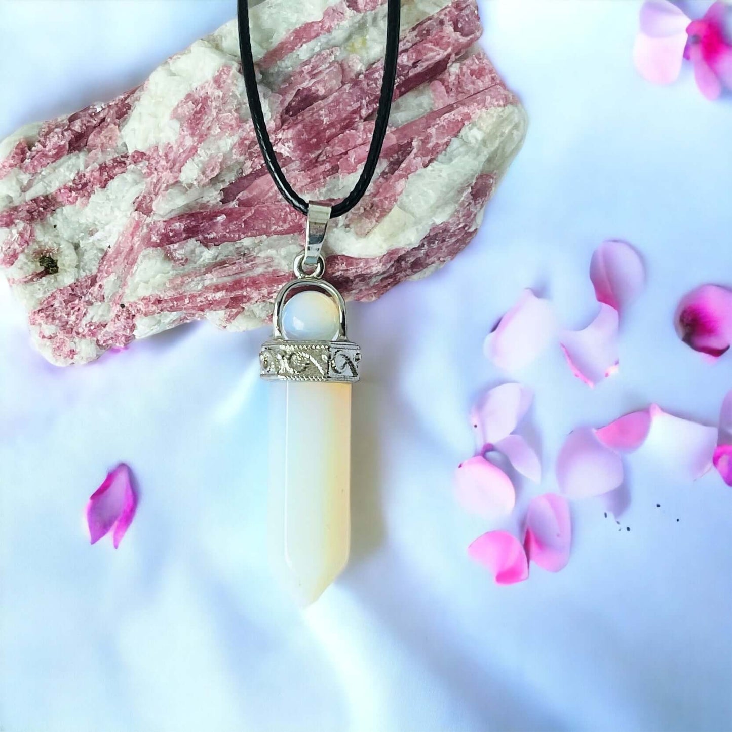 Opalite pendant on white surface with petals.