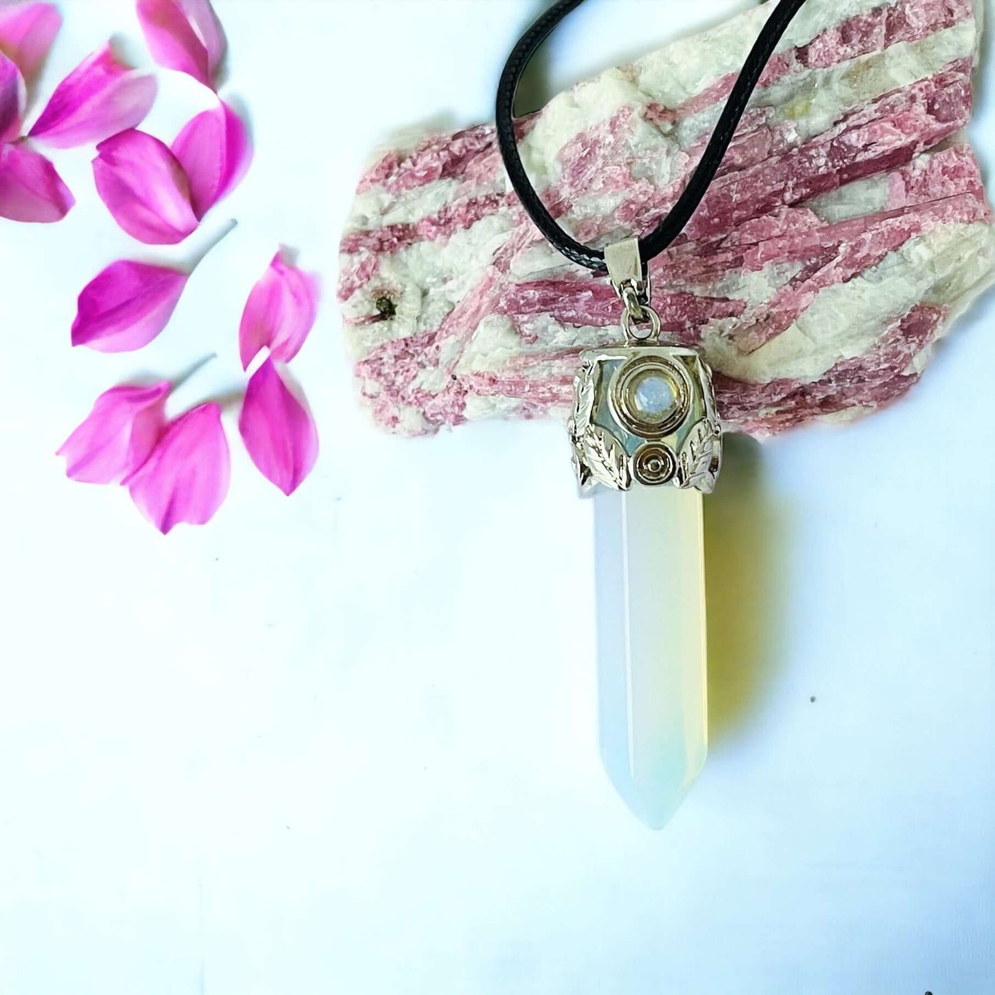 Opalite pendant on white surface with petals