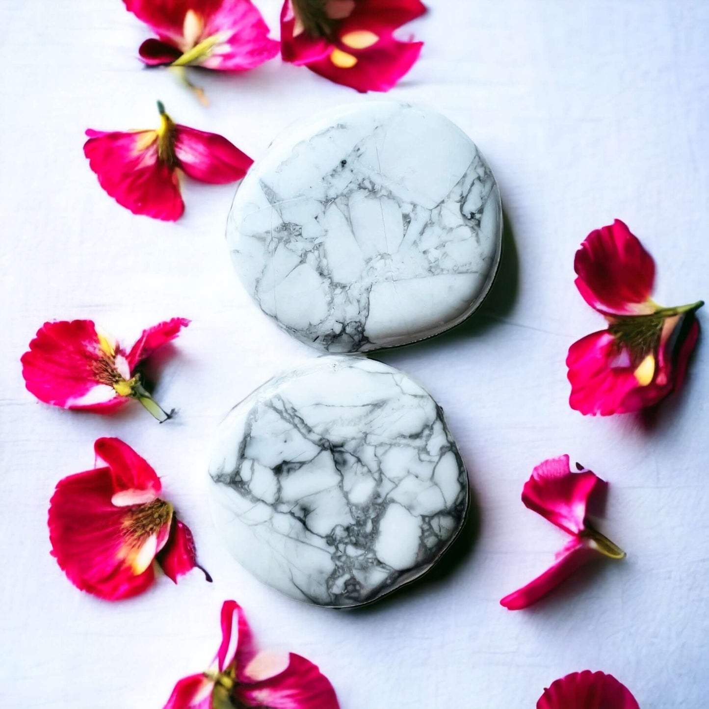 White Howlite crystal pop sockets on white surface with scattered petals.