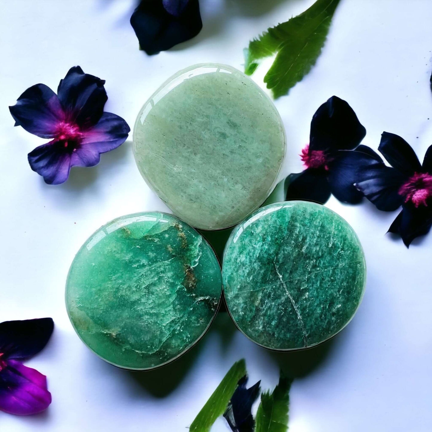 Green aventurine crystal pop sockets on white surface with scattered petals.