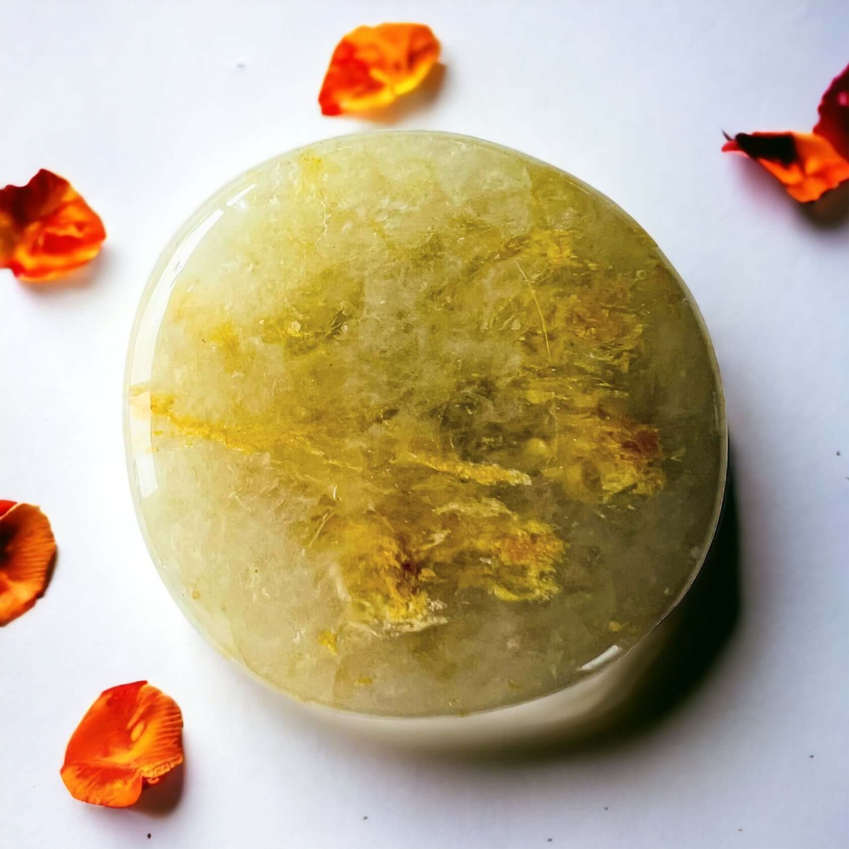 Golden healer crystal pop sockets on white surface with scattered petals.