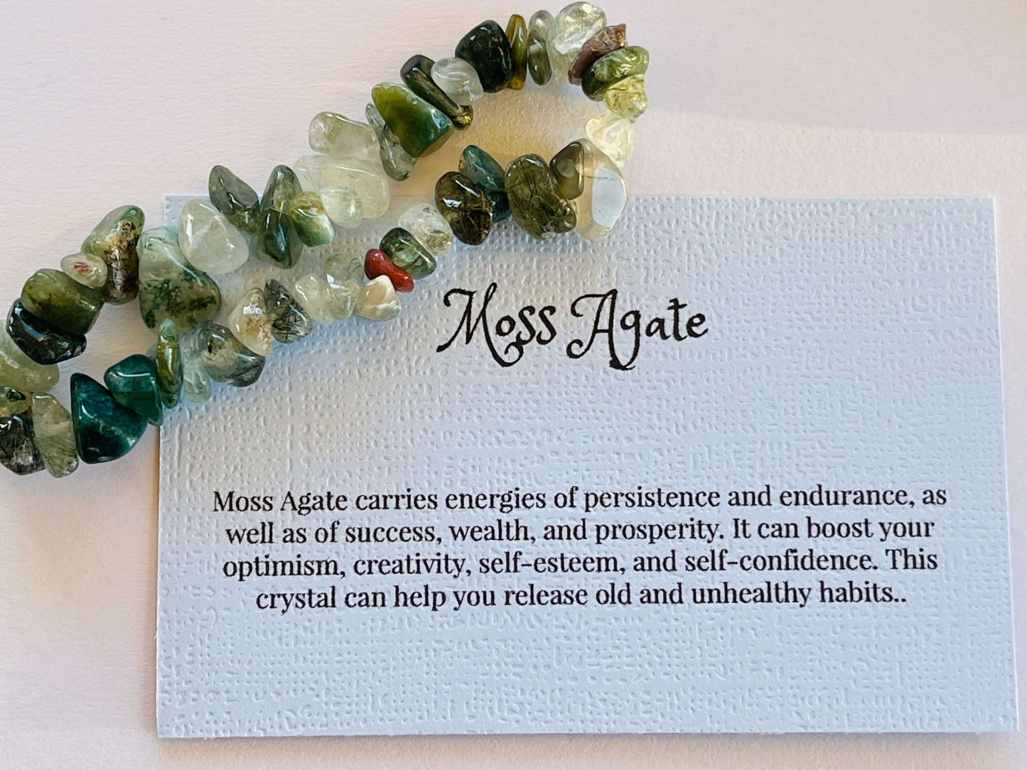 Moss agate crystal chip bracelet with information card on white background