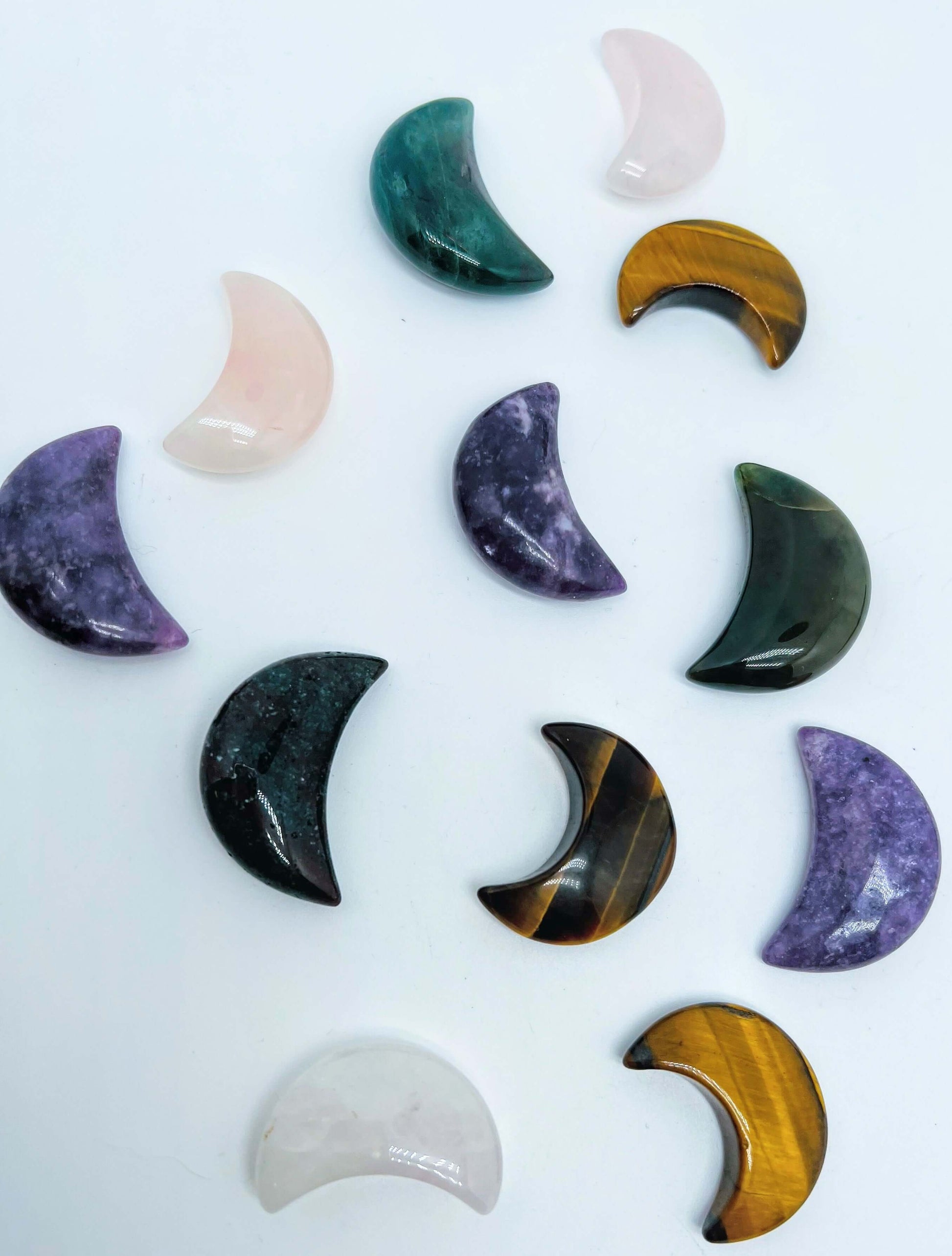 Several carved Crystal moons of different crystal stones on white background 