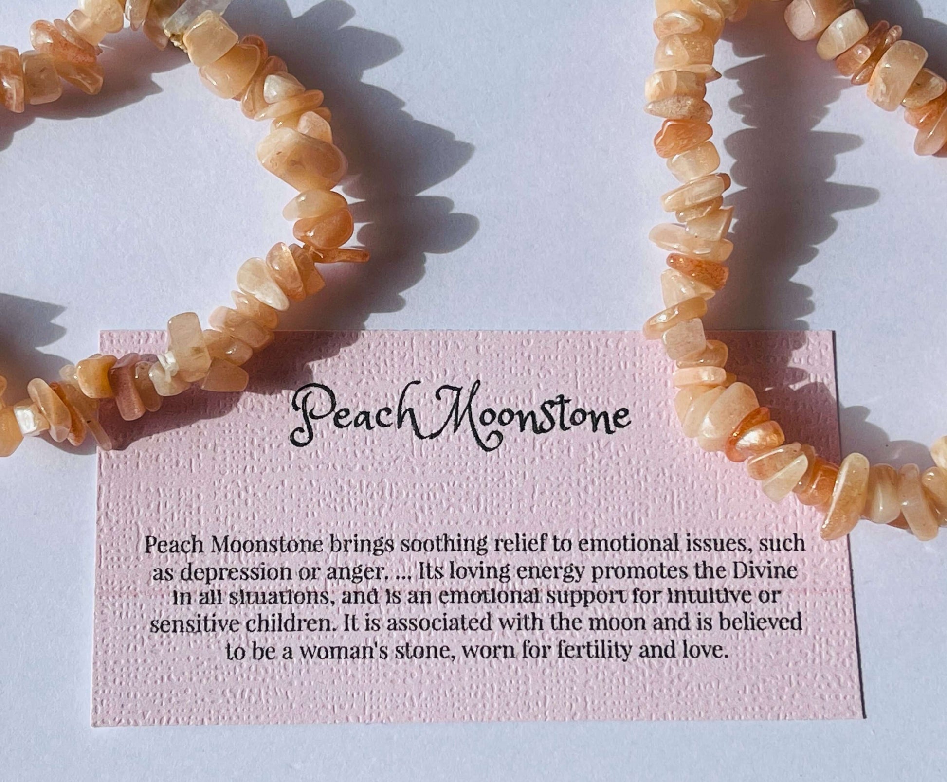 Peach moonstone crystal chip bracelet with information card on white background