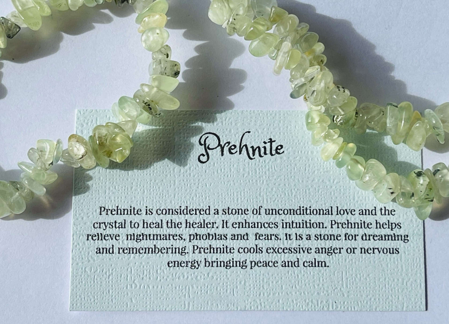 Prehnite crystal chip bracelet with information card on white background