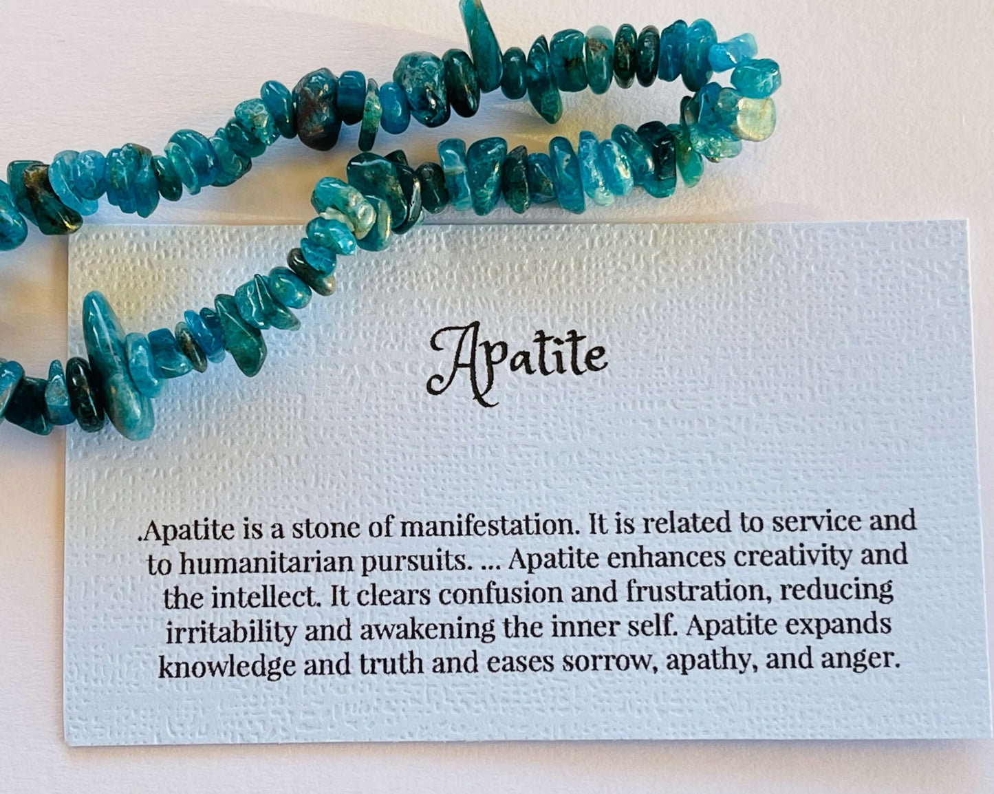 Apatite crystal chip bracelet with information card on white background