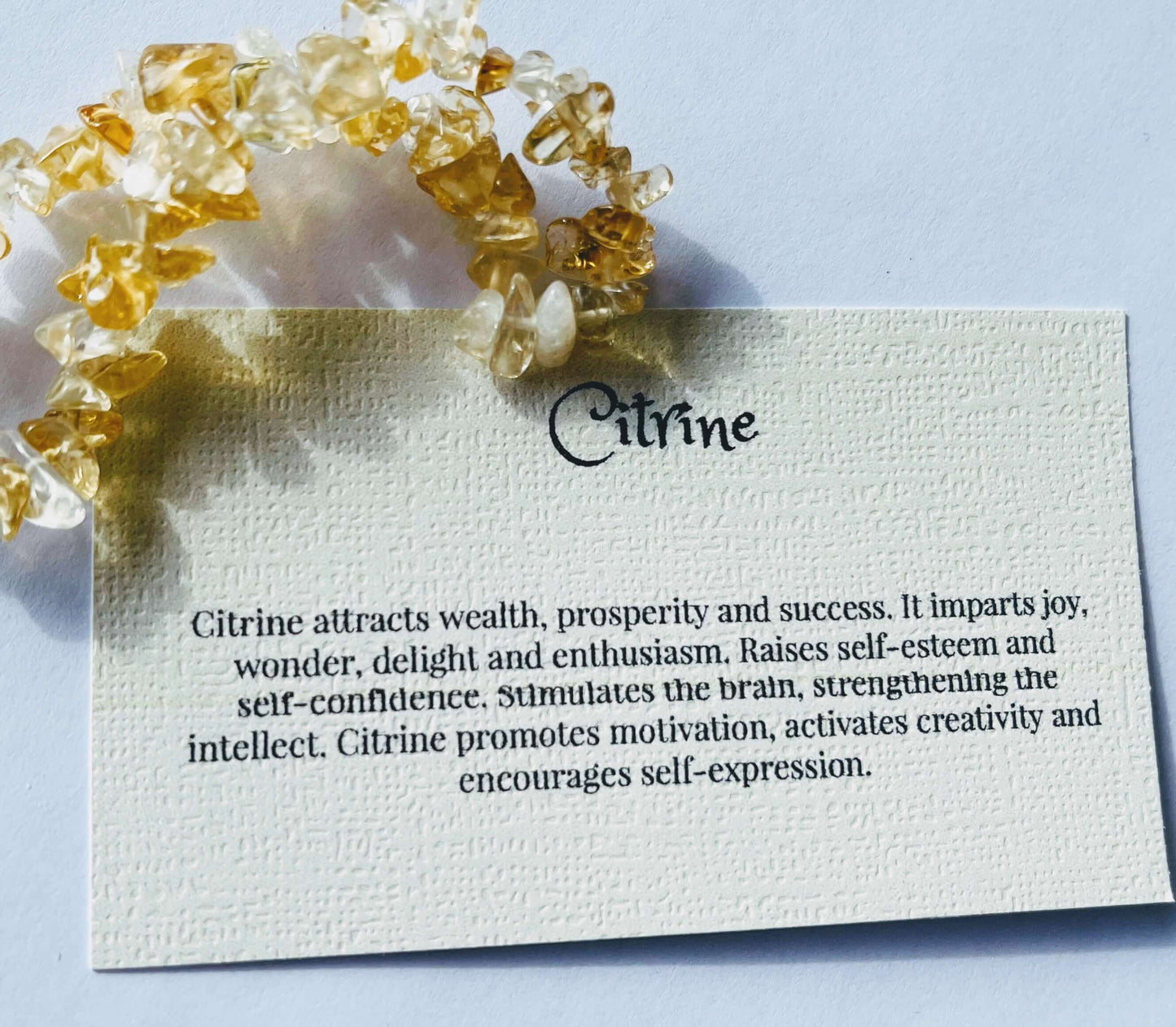 Citrine crystal chip bracelet with information card on white background