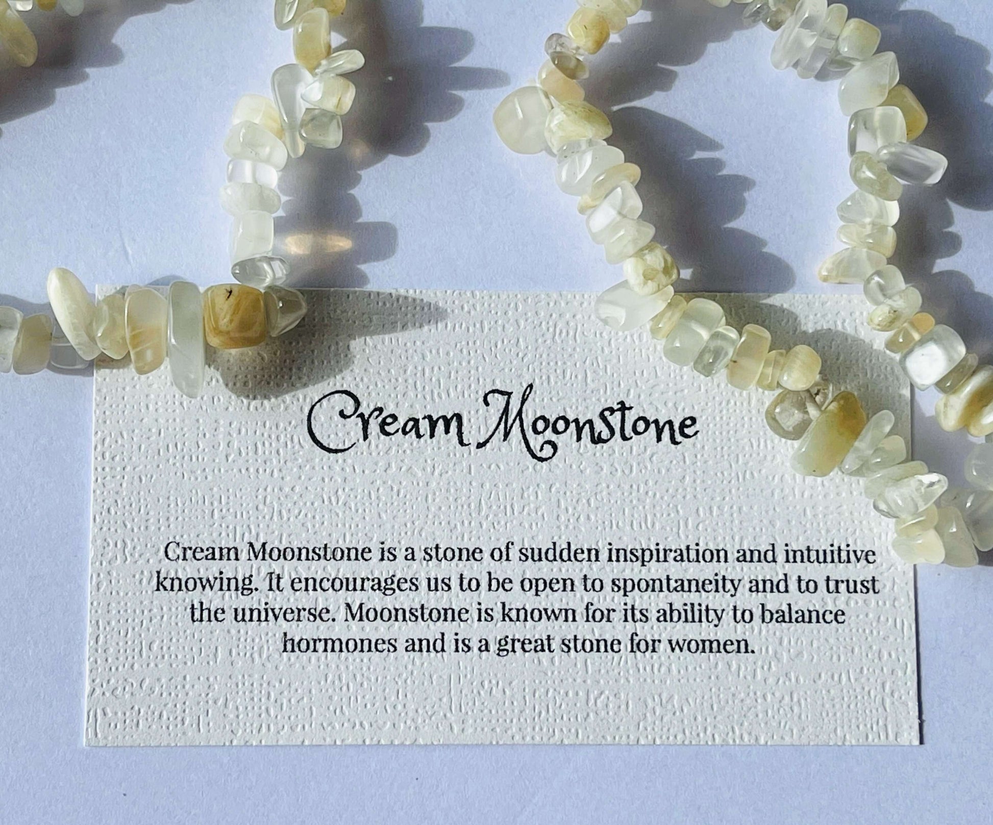 Cream moonstone crystal chip bracelet with information card on white background