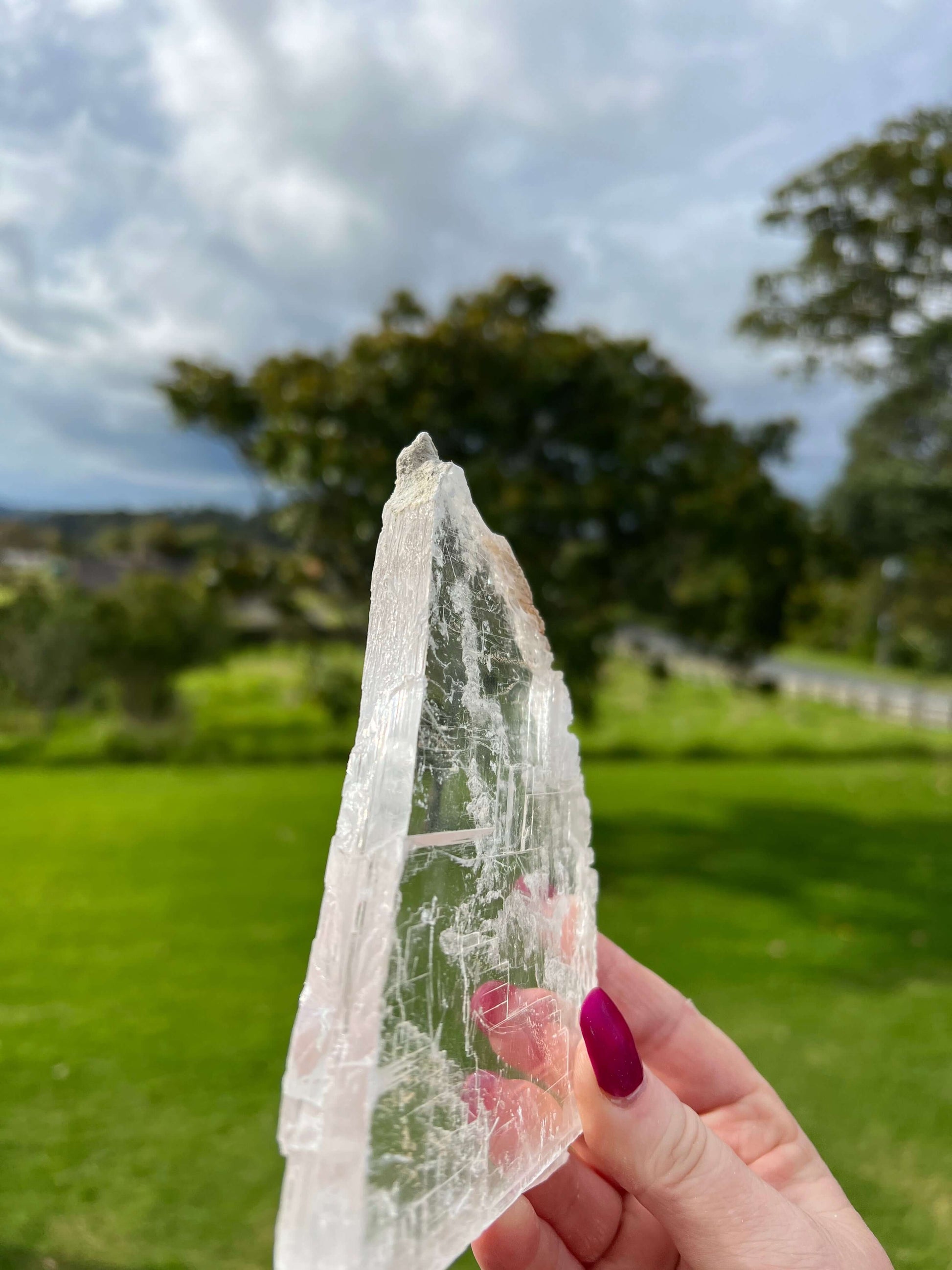 Clear selenite crystal slab with farm land in background