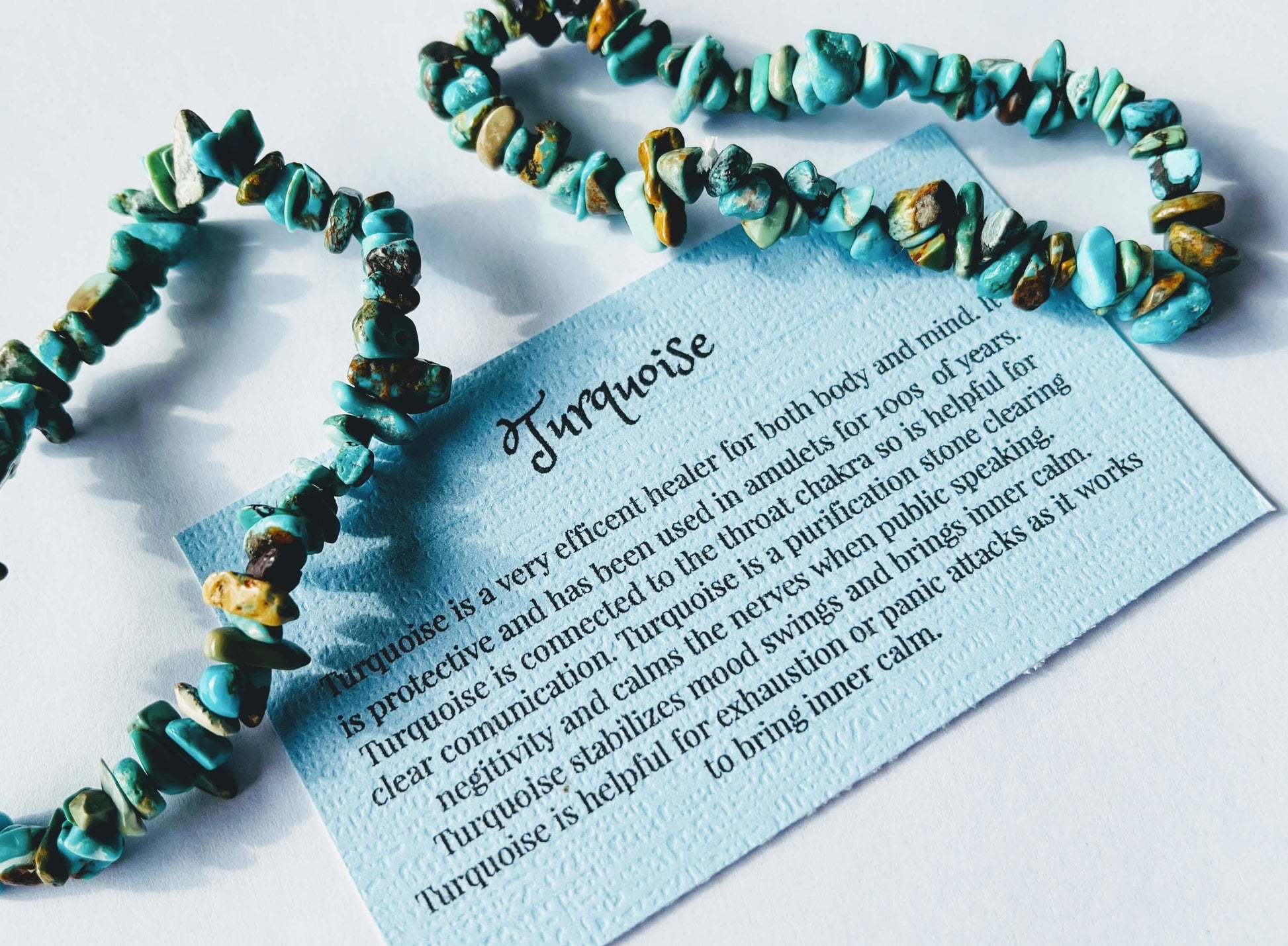 Turquoise crystal chip bracelet with information card on white background