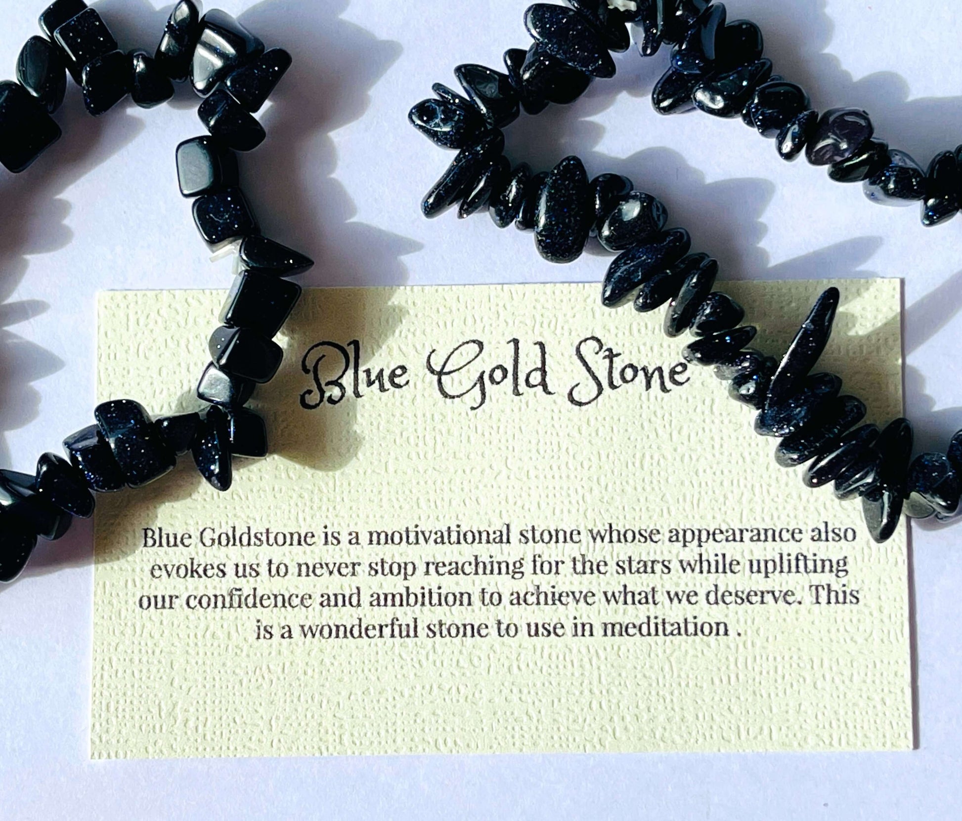 Blue goldstone crystal chip bracelet with information card on white background