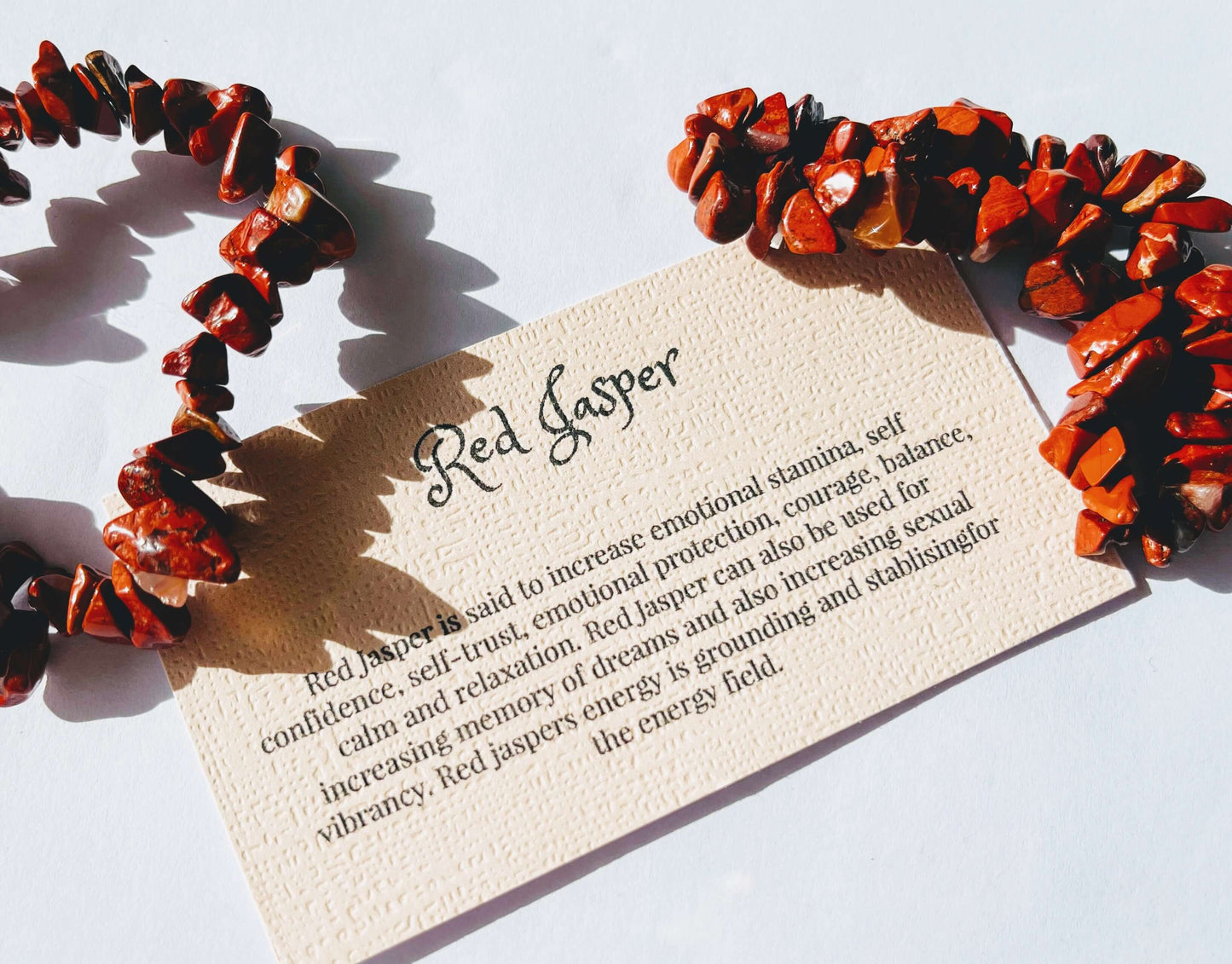 Red jasper crystal chip bracelet with information card on white background