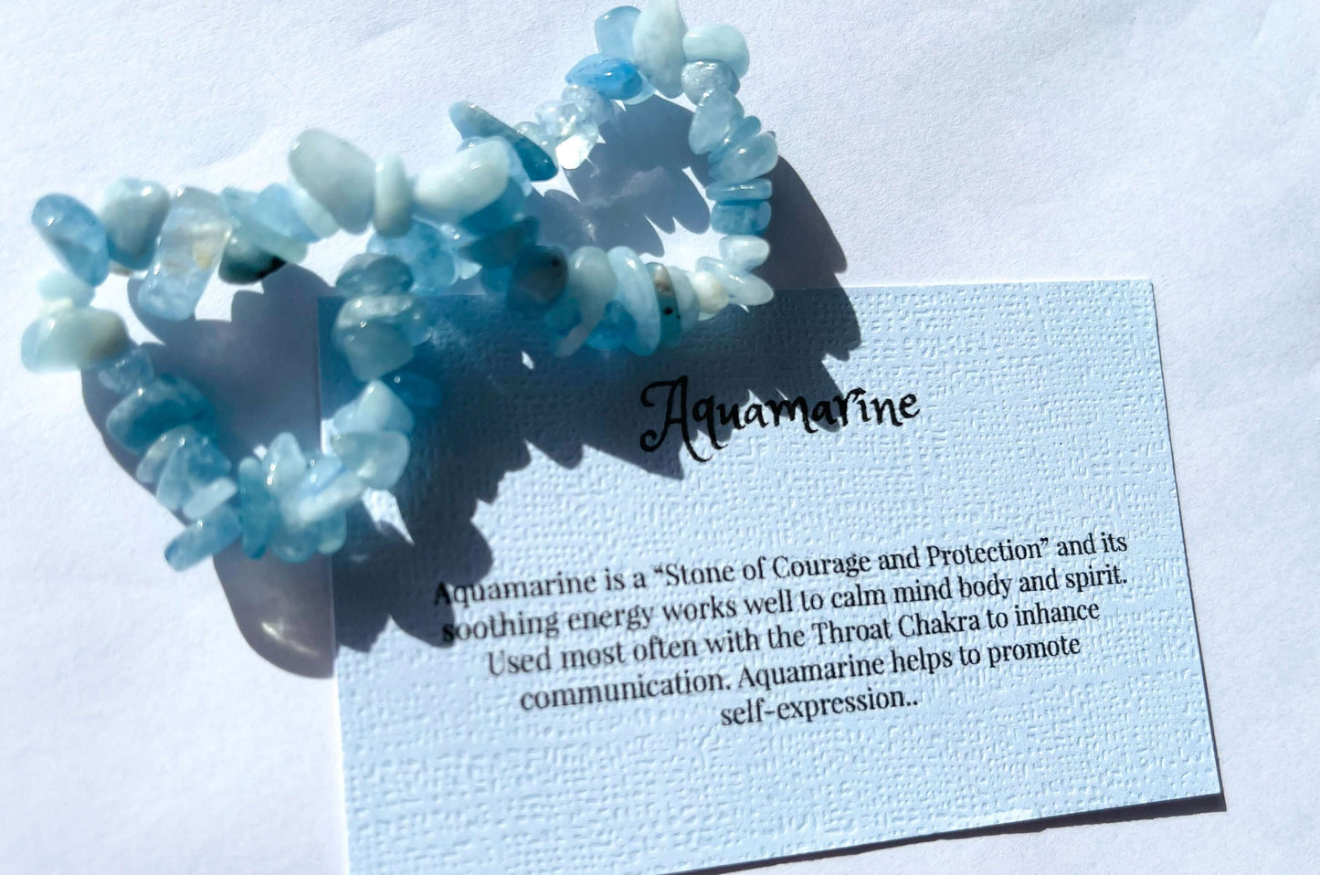 Aquamarine crystal chip bracelet with information card on white background 