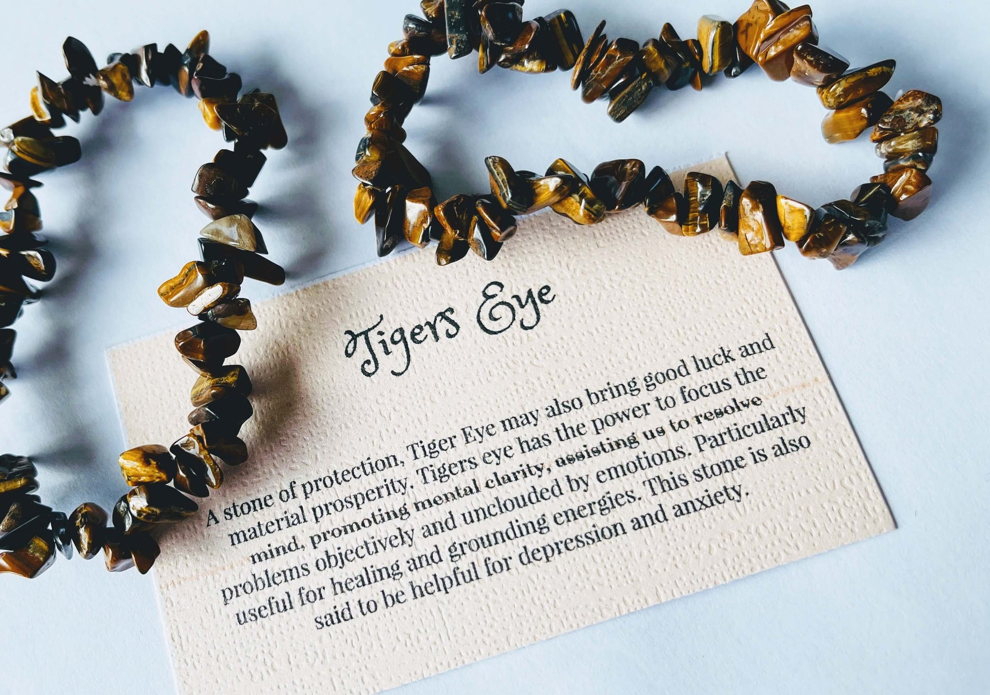 Tiger's eye crystal chip bracelet with information card on white background