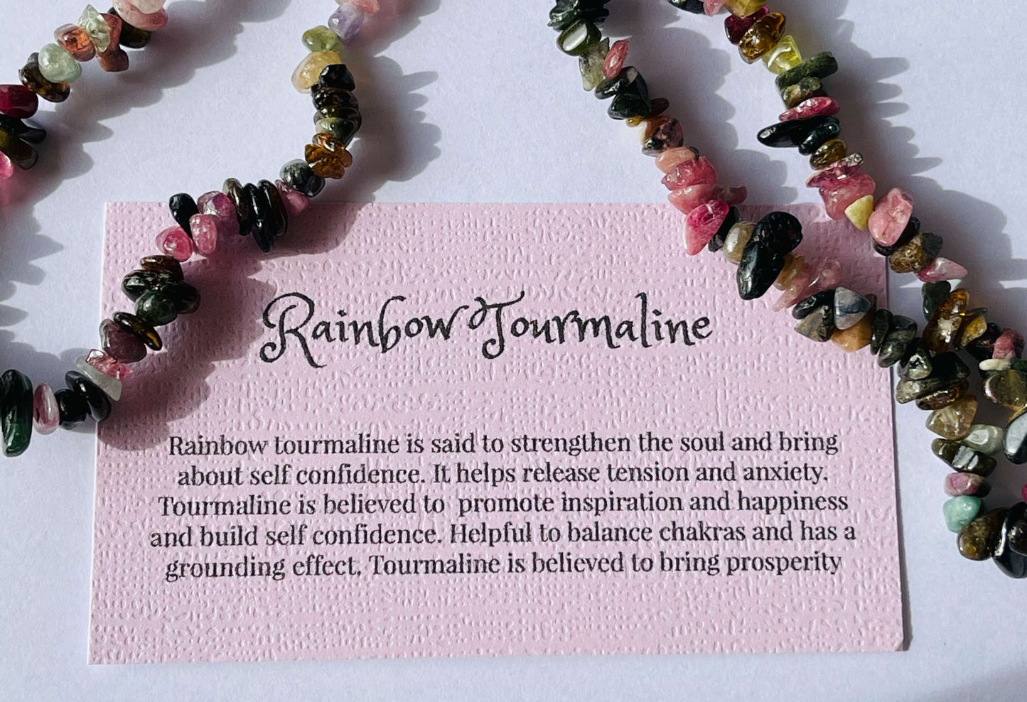 Rainbow tourmaline crystal chip bracelet with information card on white background