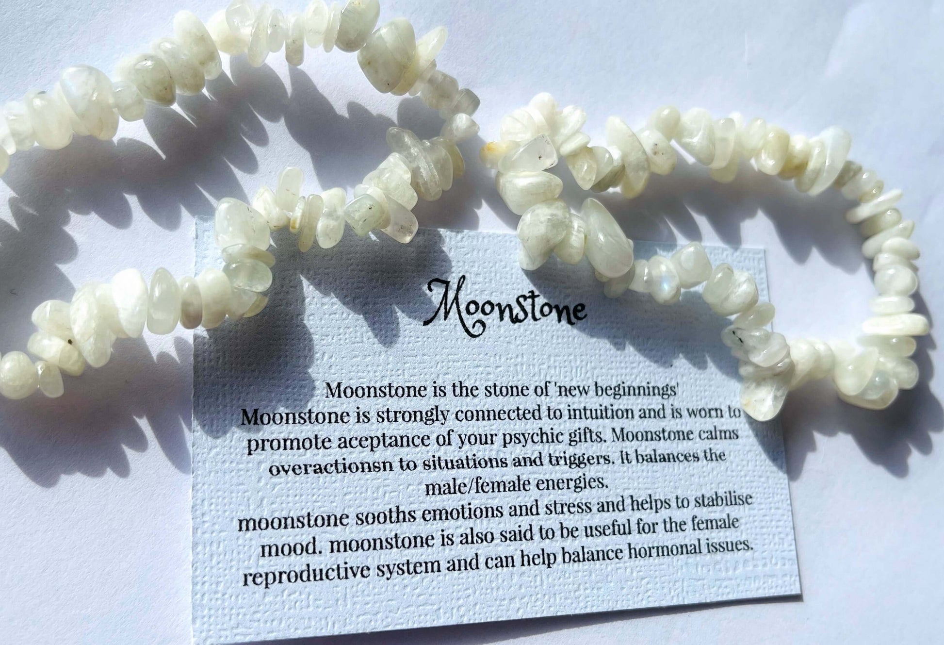 Moonstone crystal chip bracelet with information card on white background