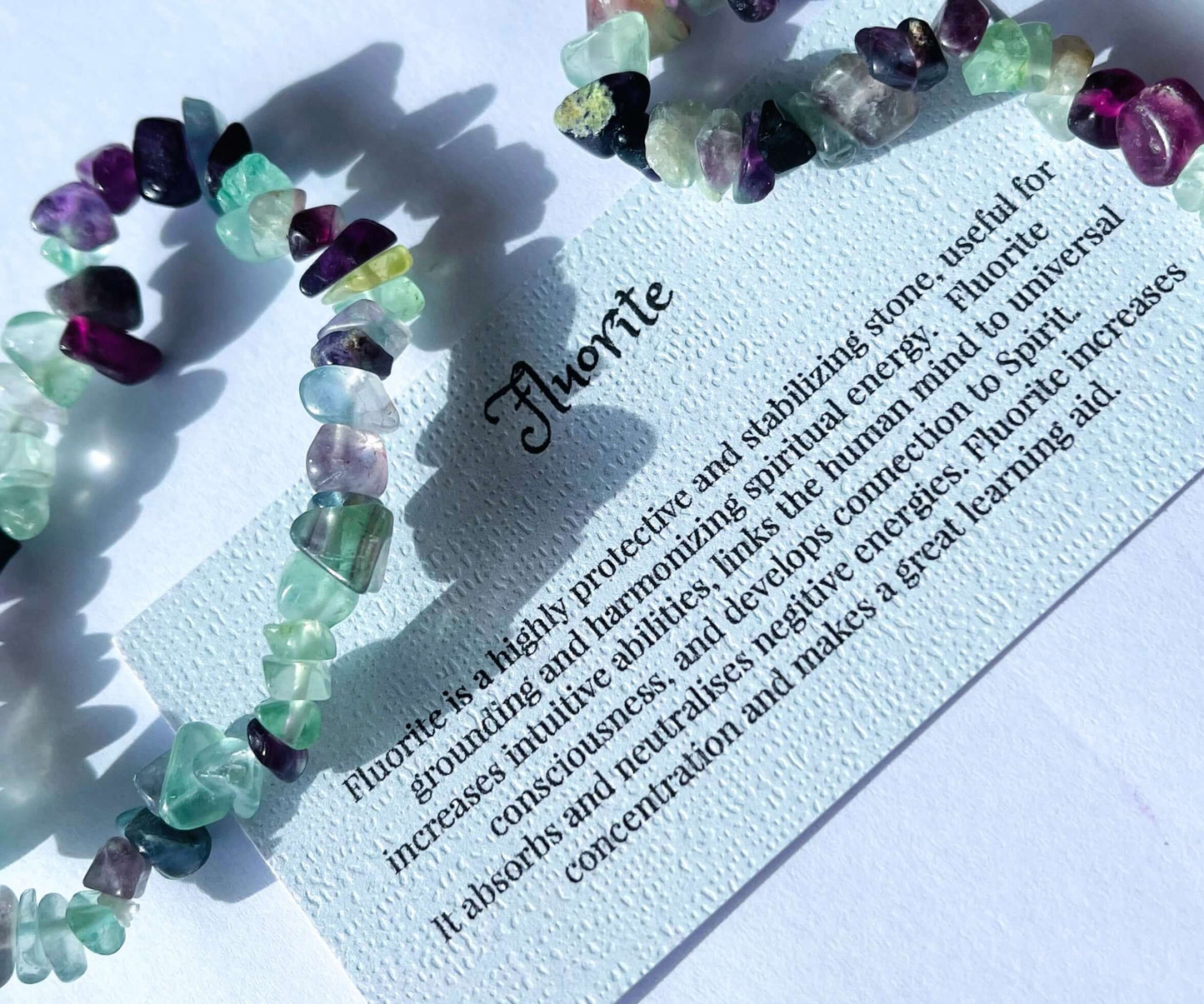 Fluorite crystal chip bracelet with information card on white background